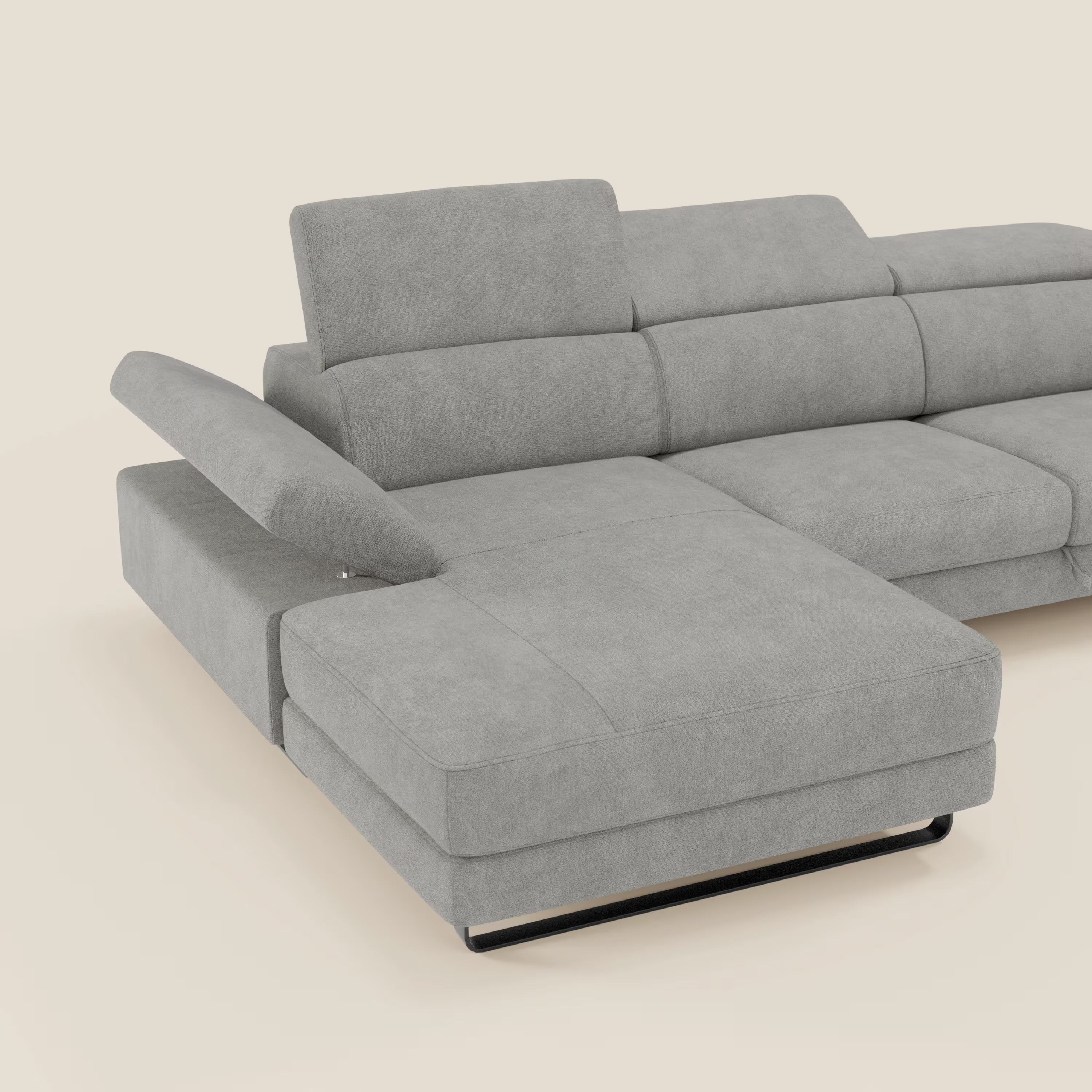 Il divano angolare estraibile Zayana di Divani.Store è caratterizzato da braccioli e poggiatesta reclinabili in tessuto impermeabile T02 grigio chiaro, appoggiati su gambe basse in metallo nero e da una chaise lounge allungata, su uno sfondo bianco sporco.