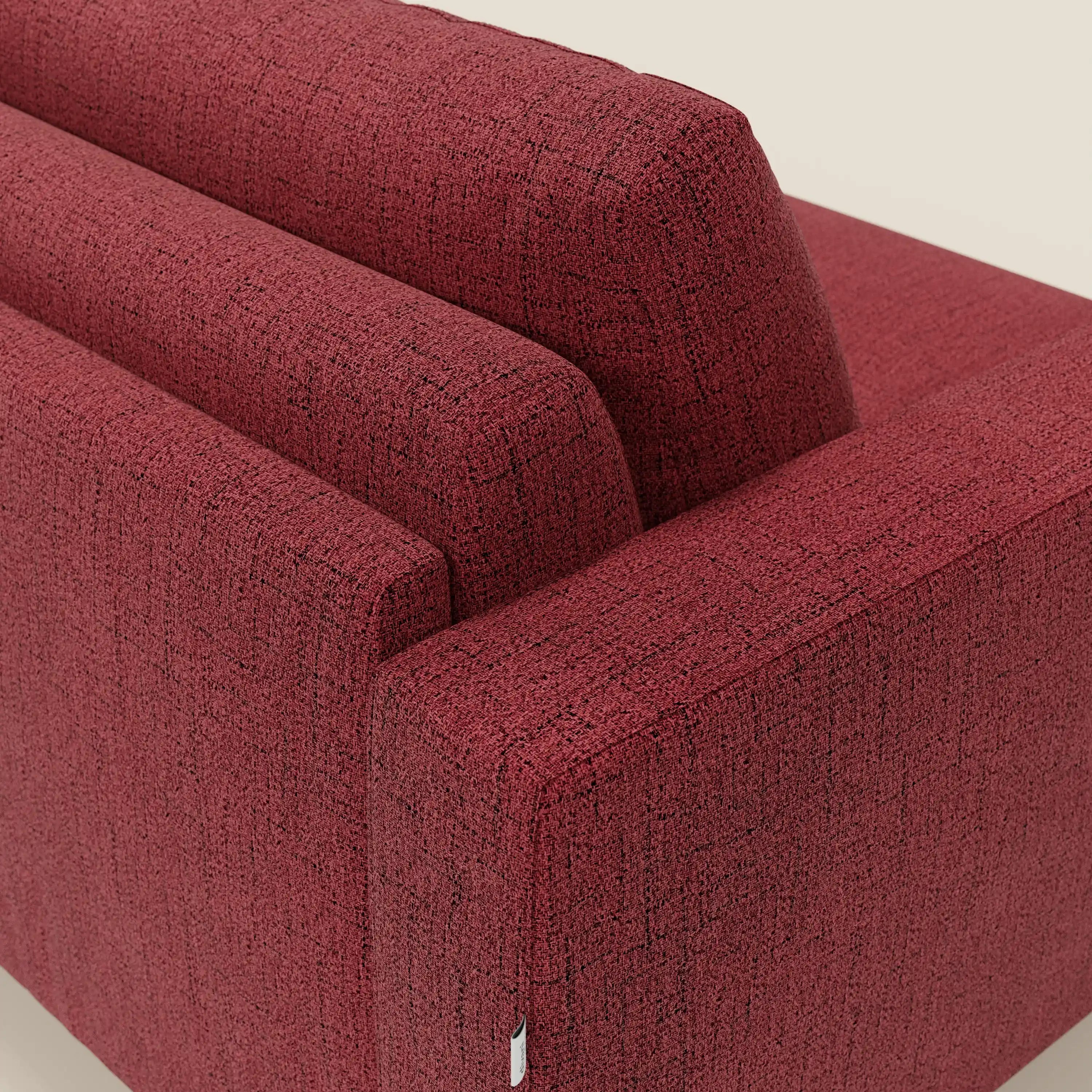 Primo piano del letto matrimoniale Alaya Divano di Divani.Store, caratterizzato da morbidi cuscini in tessuto impermeabile rosso T03 con un sottile dettaglio in filo nero. L'immagine evidenzia lo schienale e il bracciolo su uno sfondo beige chiaro.