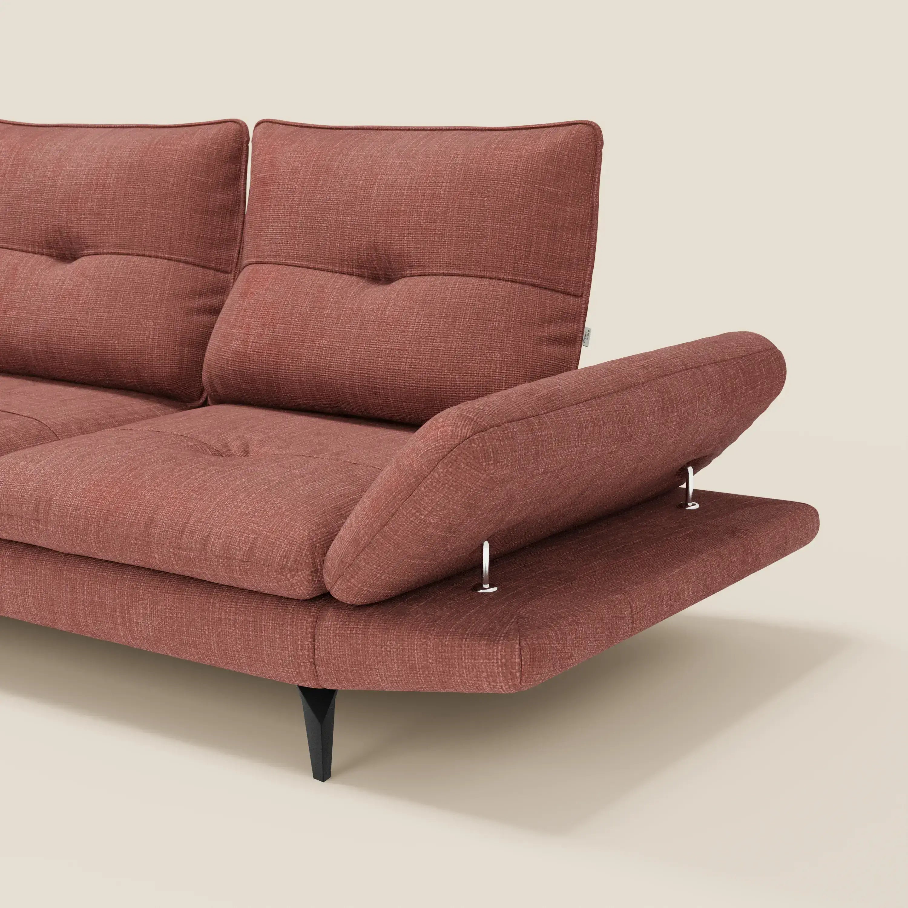 Un moderno Divano Angolare Ardex di Divani.Store in tessuto impermeabile T06 corallo con gambe nere. Presenta un bracciolo regolabile sostenuto da due aste metalliche e schienali traslanti. Su uno sfondo beige semplice, viene mostrata solo una parte del divano.