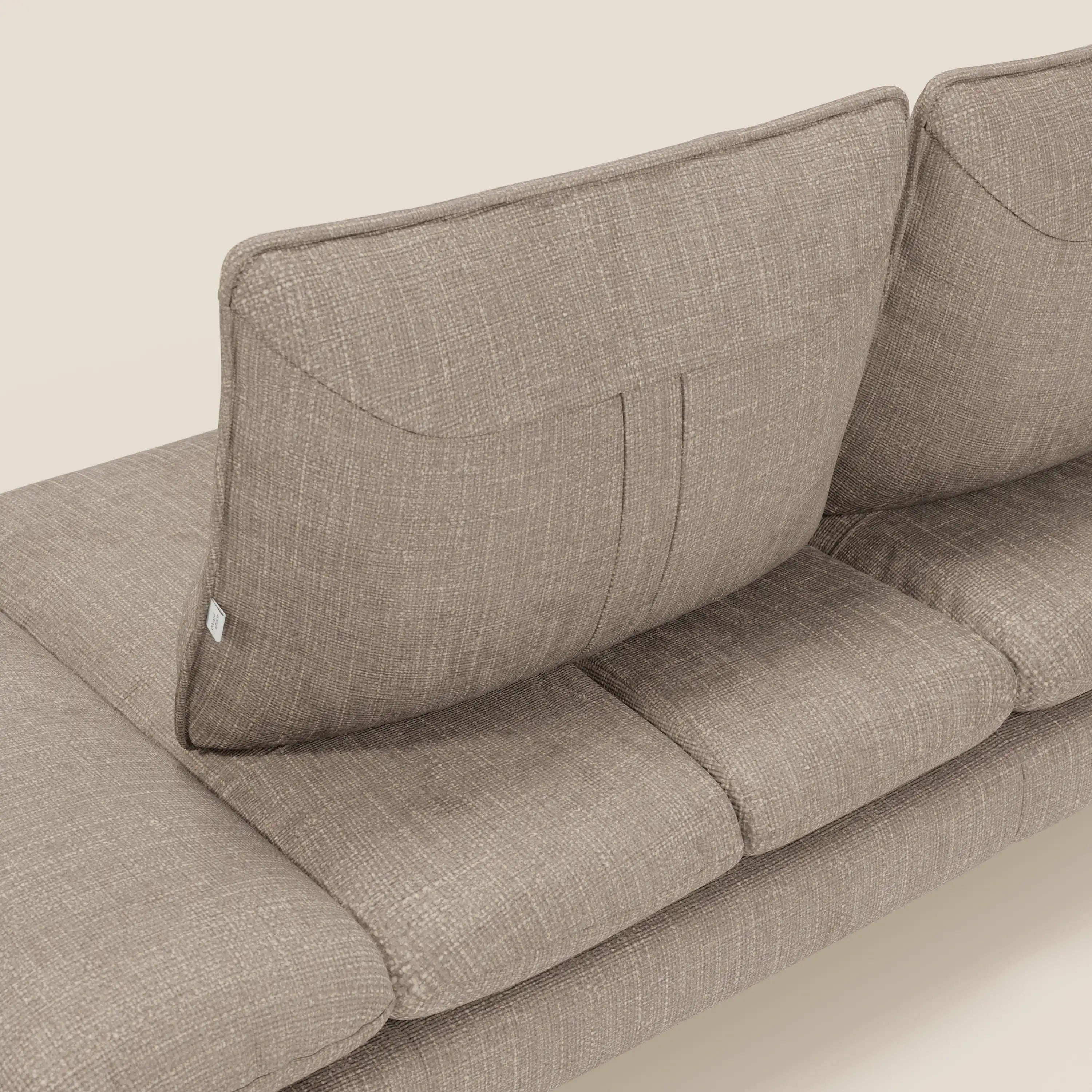 Primo piano di Ardex Divano 3 posti di Divani.Store in morbido tessuto impermeabile T06 tortora, caratterizzato da schienali traslanti, braccioli regolabili e raffinate cuciture per un comfort personalizzato su uno sfondo chiaro.