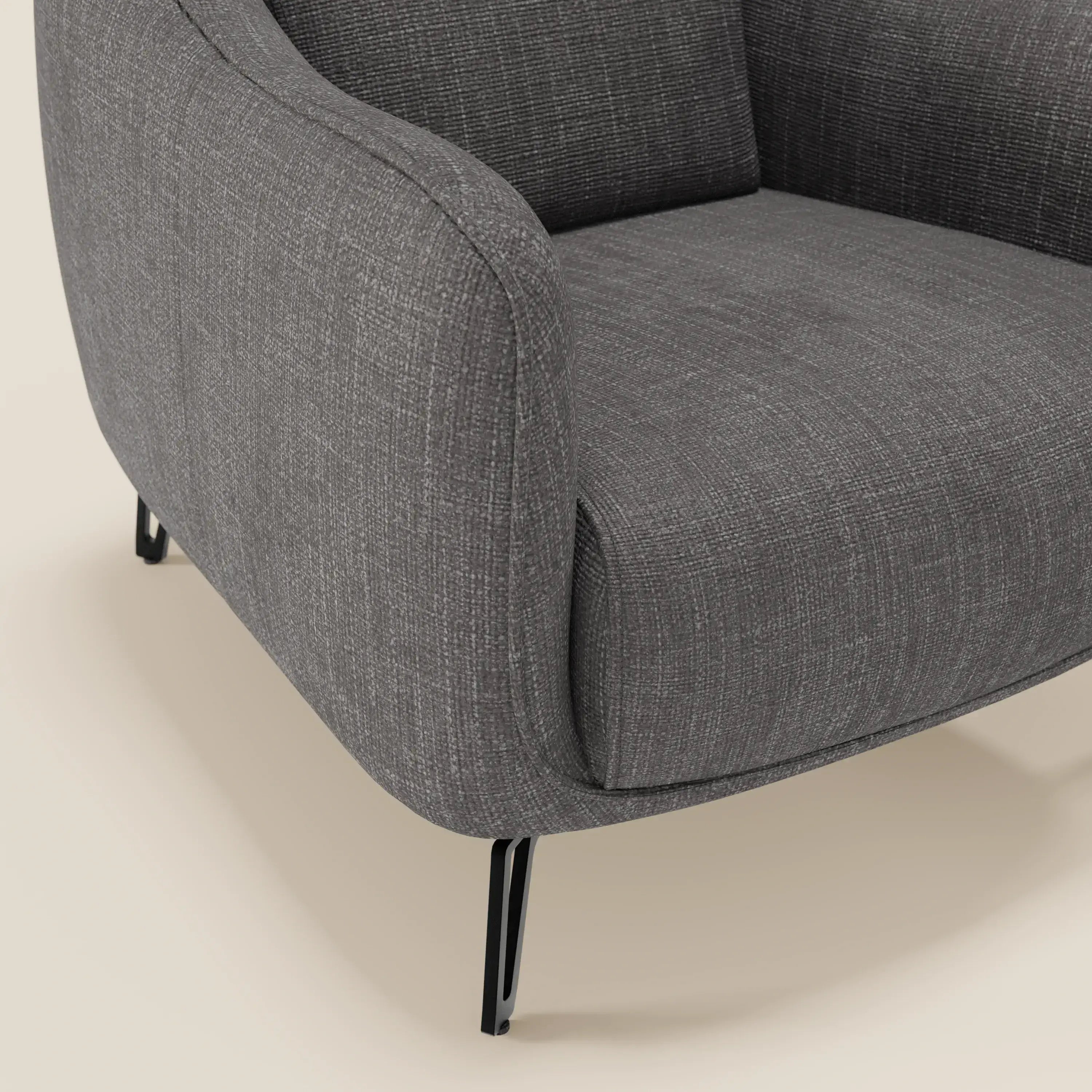 Primo piano di Avela Poltroncina di Divani.Store, caratterizzata da un comfort senza tempo in morbido tessuto T06 antracite resistente all'acqua e da braccioli delicatamente curvati. Si regge su eleganti gambe in metallo nero, per un design elegante.