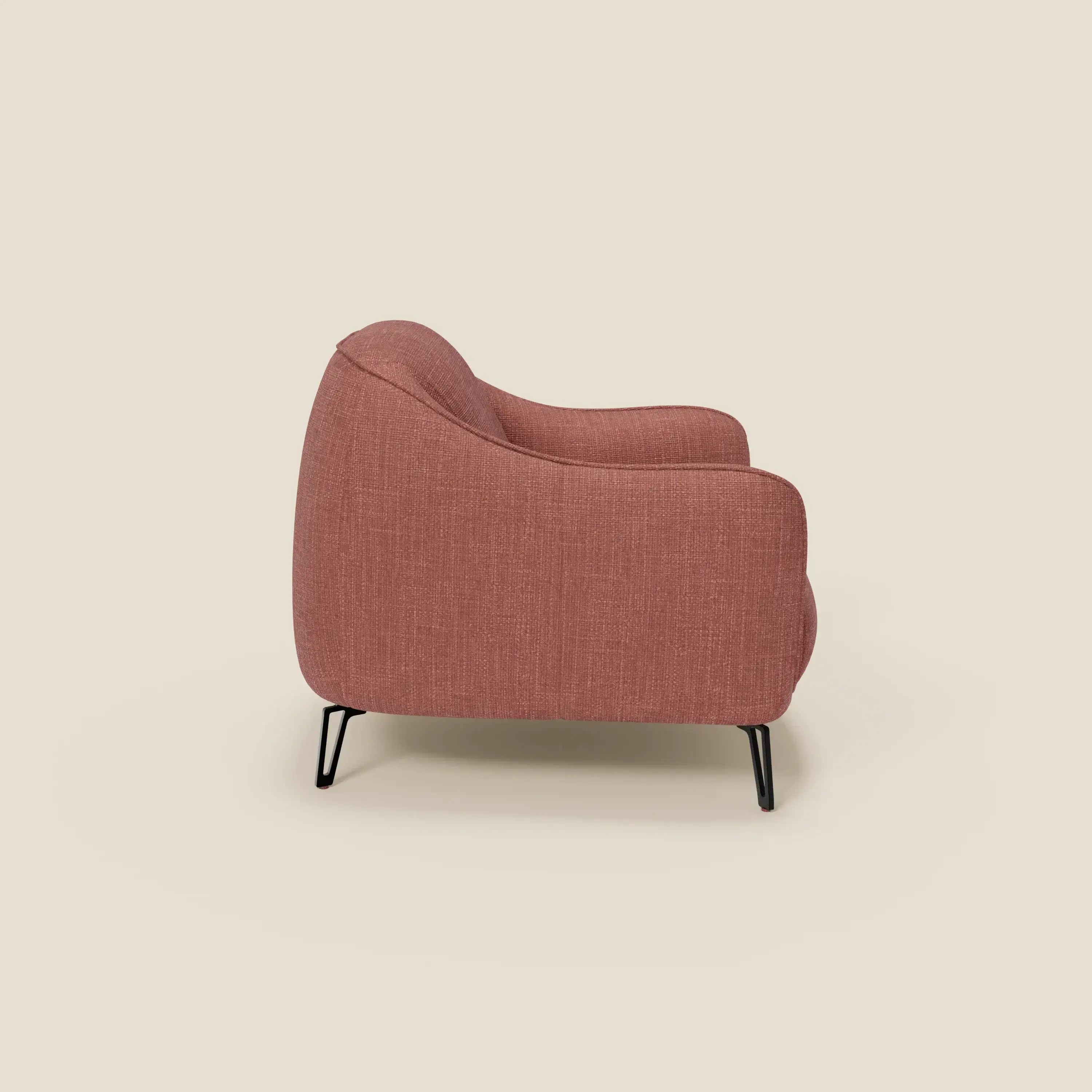 Vista laterale di Avela Poltroncina di Divani.Store, una poltrona moderna dalle curve morbide, con schienale reclinato e sottili gambe in metallo nero, rivestita in morbido tessuto impermeabile T06 corallo su sfondo beige.