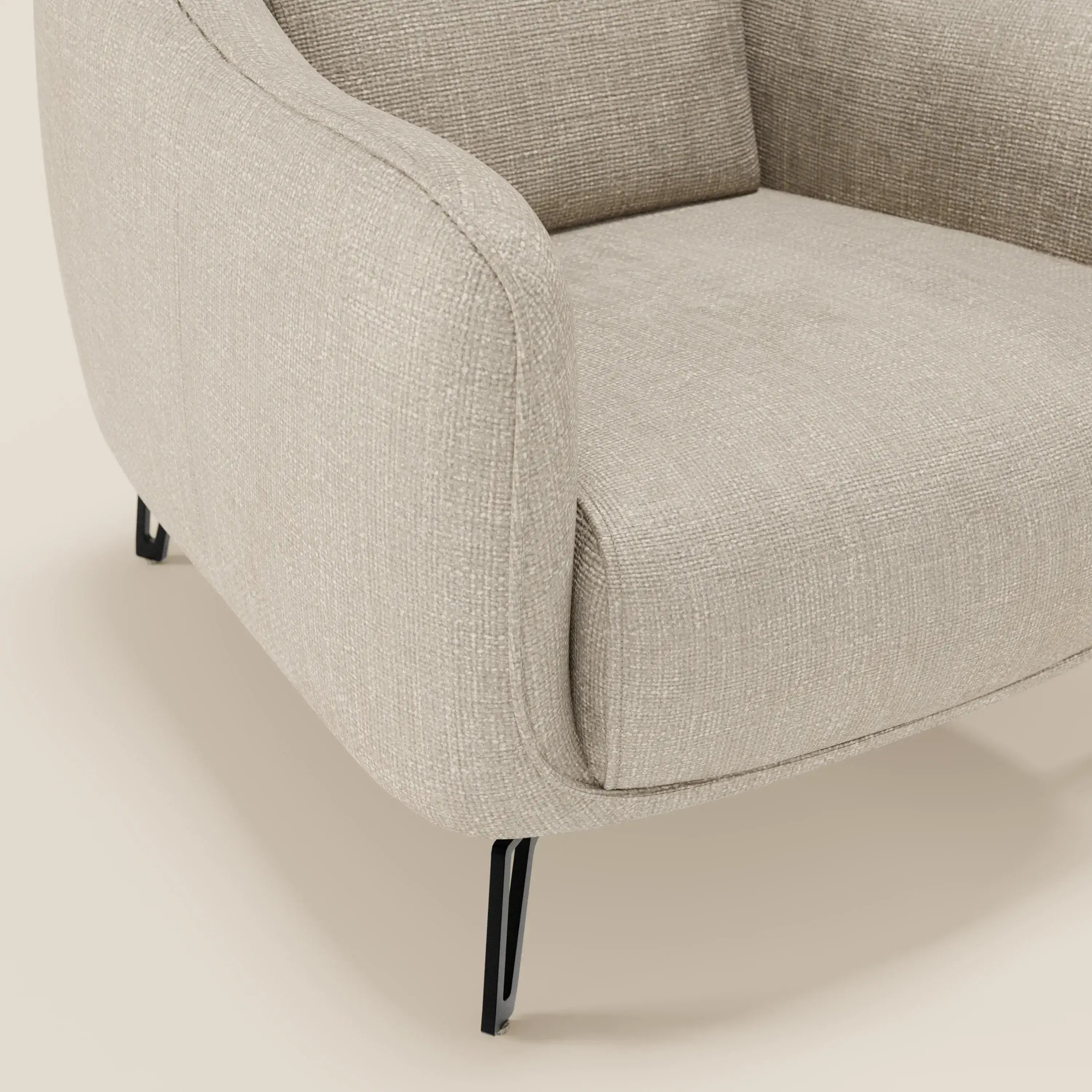 Primo piano della poltroncina Avela di Divani.Store, dal design moderno in morbido tessuto impermeabile T06 panna. Le curve morbide e le sottili gambe in metallo nero ne sottolineano la comodità senza tempo su un pavimento chiaro.