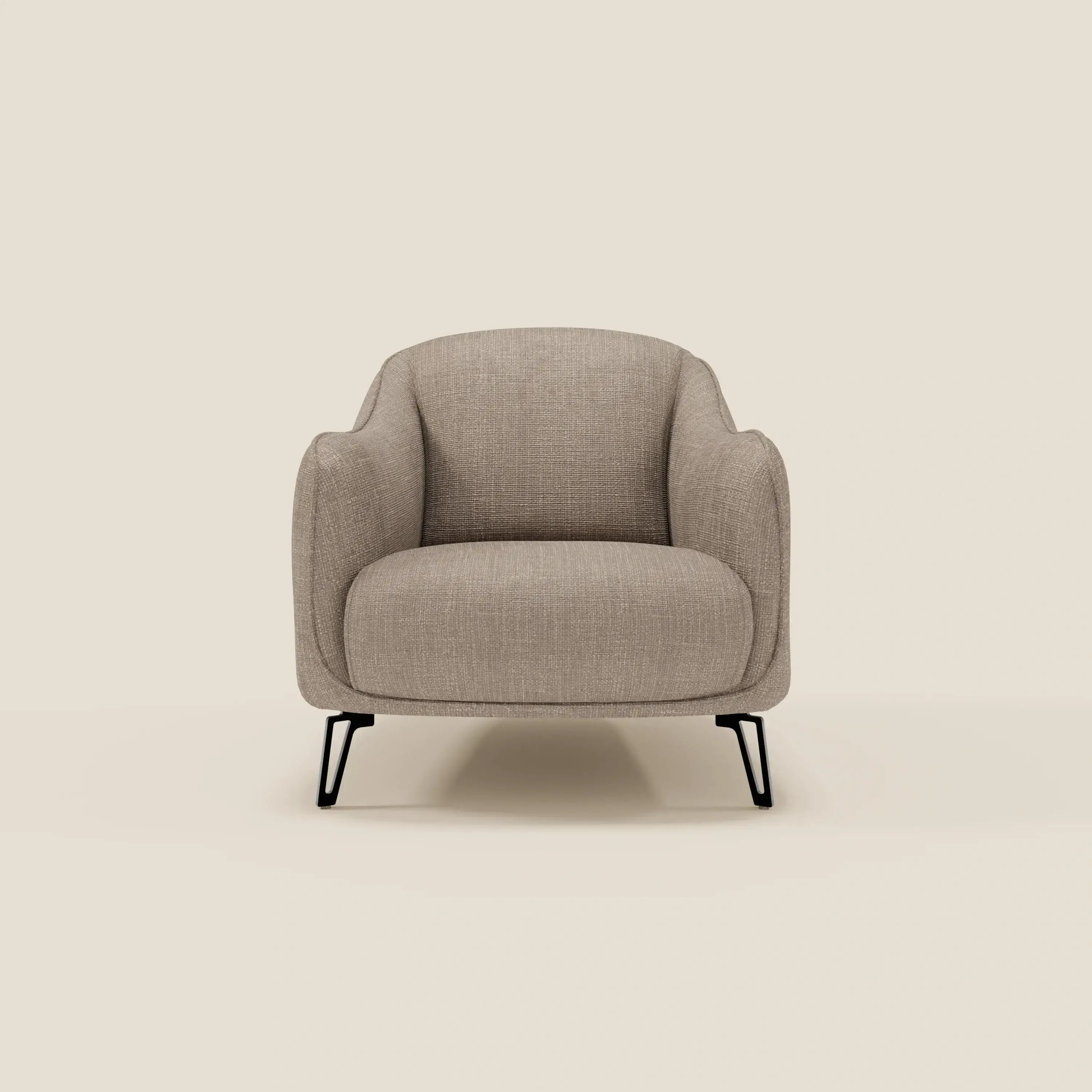 La poltroncina Avela di Divani.Store, in morbido tessuto impermeabile T06 tortora e sottili gambe in metallo nero, è caratterizzata da un design minimalista e contemporaneo, con braccioli e schienale curvi, su uno sfondo beige semplice.