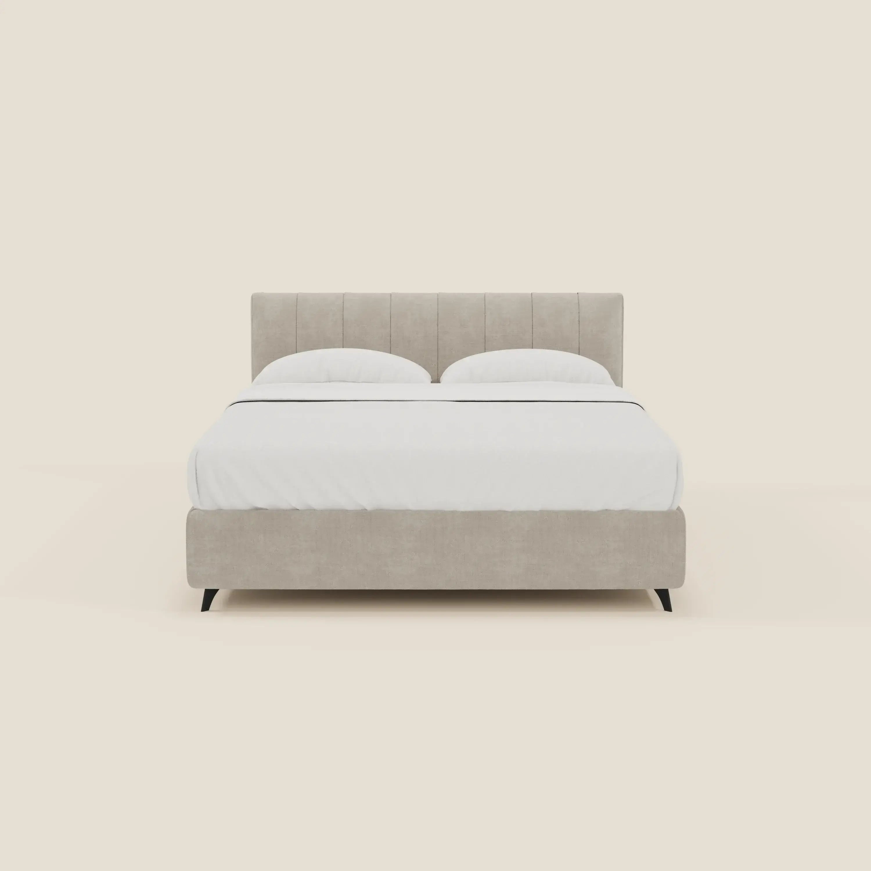 Un letto contenitore Bogart Edizione Grande Fratello di Letti.store, sfoderabile in tessuto smacchiabile T22 panna, è caratterizzato da una testata con impunture verticali e gambe nere corte e angolate, su uno sfondo crema chiaro con biancheria da letto bianca e due cuscini.