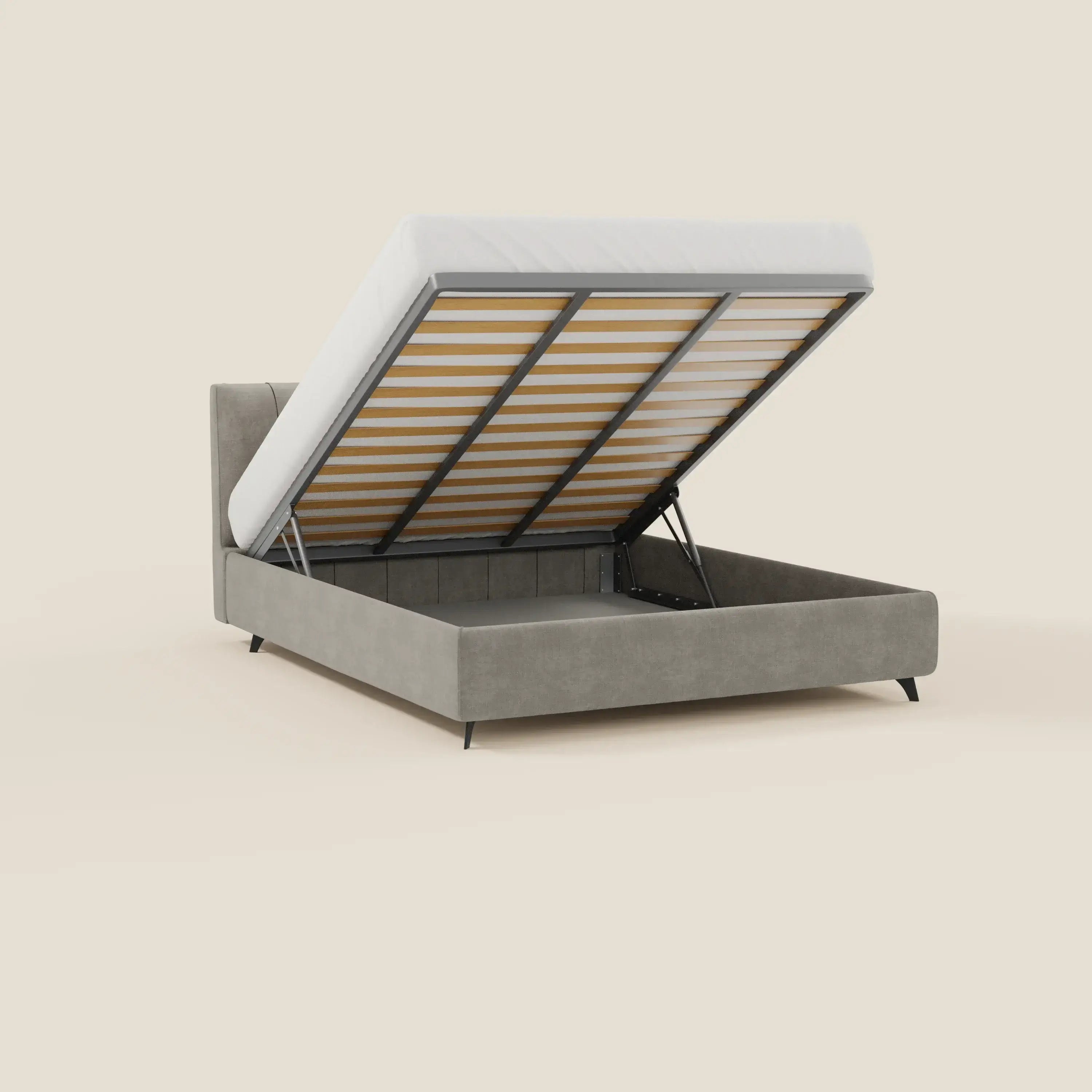 Il letto contenitore Bogart Edizione Grande Fratello di Letti.store è caratterizzato da un tessuto grigio T22 sfoderabile e antimacchia. La pedana del materasso sollevata rivela un ampio spazio di contenimento e poggia su quattro gambe con cerniere in metallo e doghe in legno. Sfondo beige semplice.