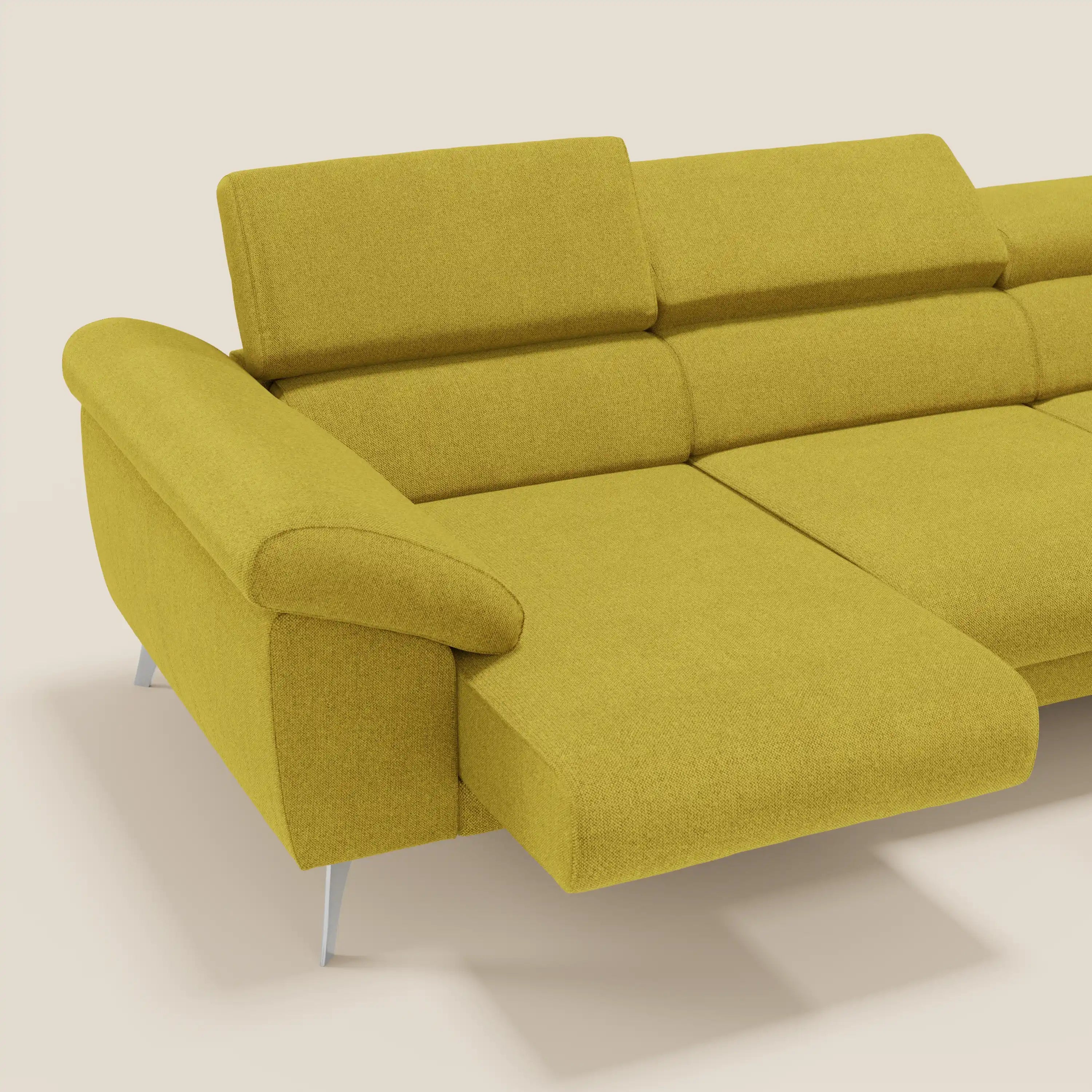 Il Divano angolare Donatello di Divani.Store, in morbido tessuto antimacchia T23 giallo sole, è caratterizzato da poggiatesta regolabili, sedute scorrevoli, braccioli portaoggetti e chaise lounge sinistra con sottili gambe in metallo argentato su sfondo chiaro.
