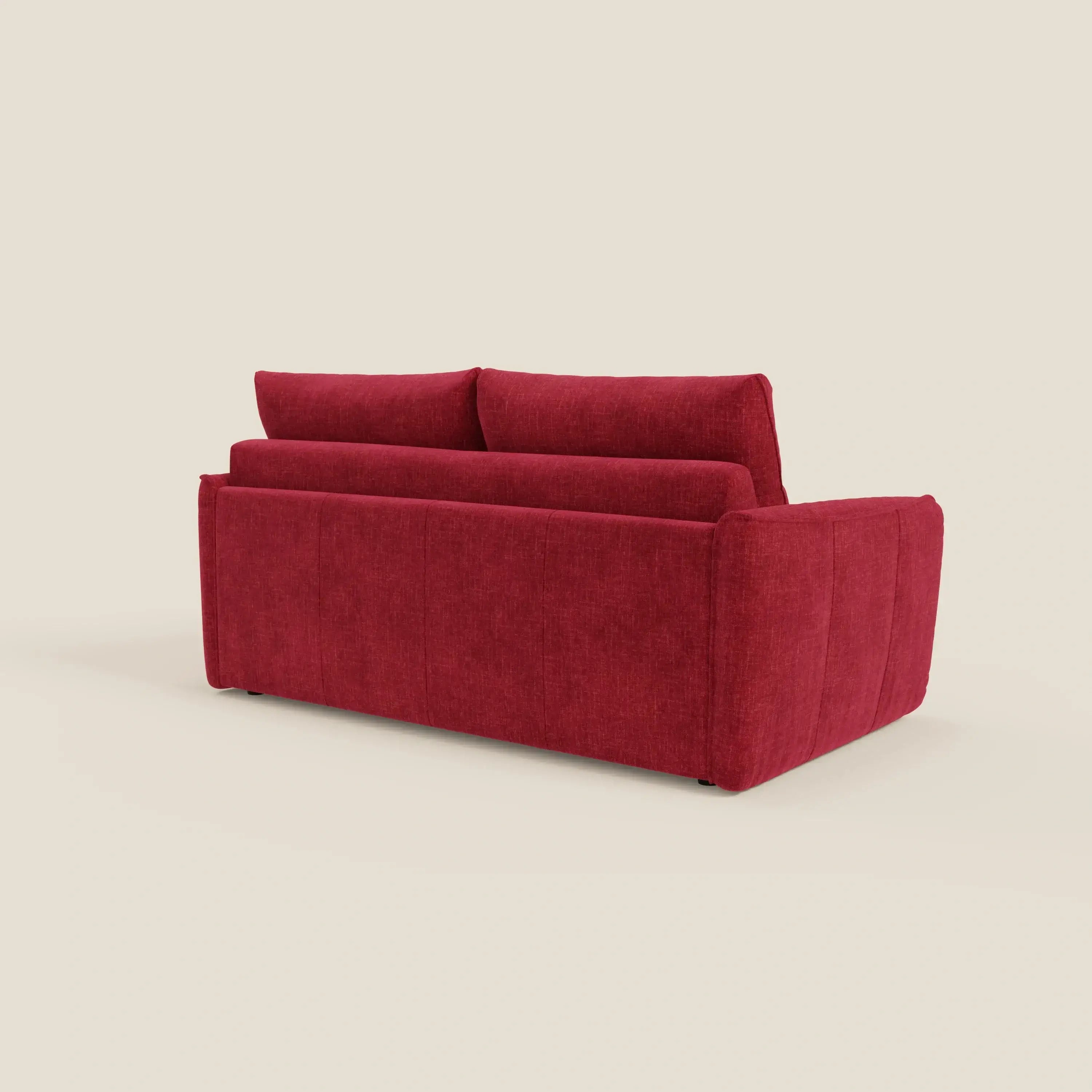 Il divano letto Elios di Divani.Store, in tessuto smacchiabile T24 rosso bordeaux, è mostrato dal retro in posizione angolata su uno sfondo beige chiaro, che mette in evidenza i cuscini dello schienale e i braccioli squadrati. Non sono visibili altri oggetti.