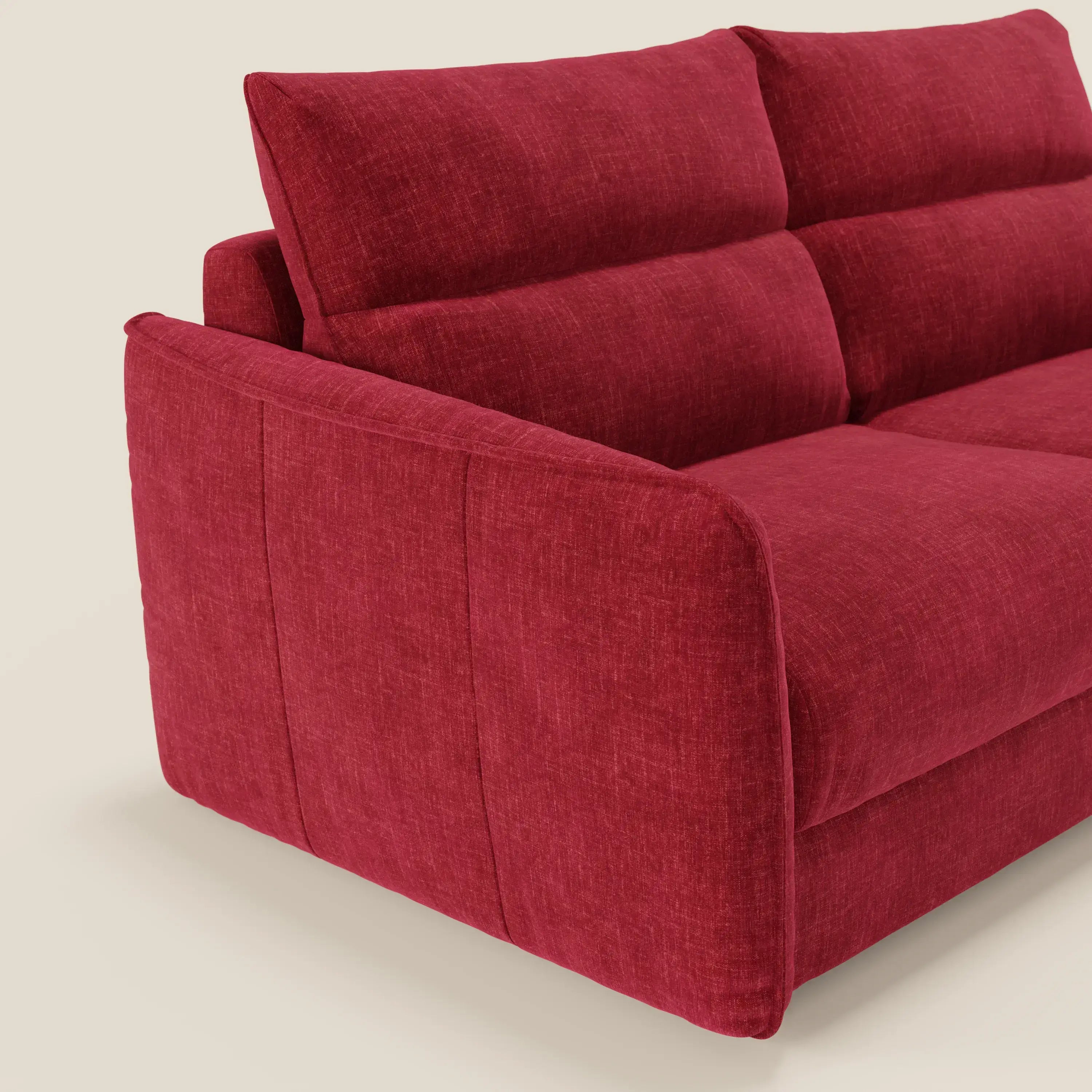 Primo piano del divano letto Elios di Divani.Store, con spalliera in cuscini morbidi e rivestimento in tessuto smacchiabile T24 rosso bordeaux, visto di lato su uno sfondo beige chiaro, con linee pulite e cuciture minime.