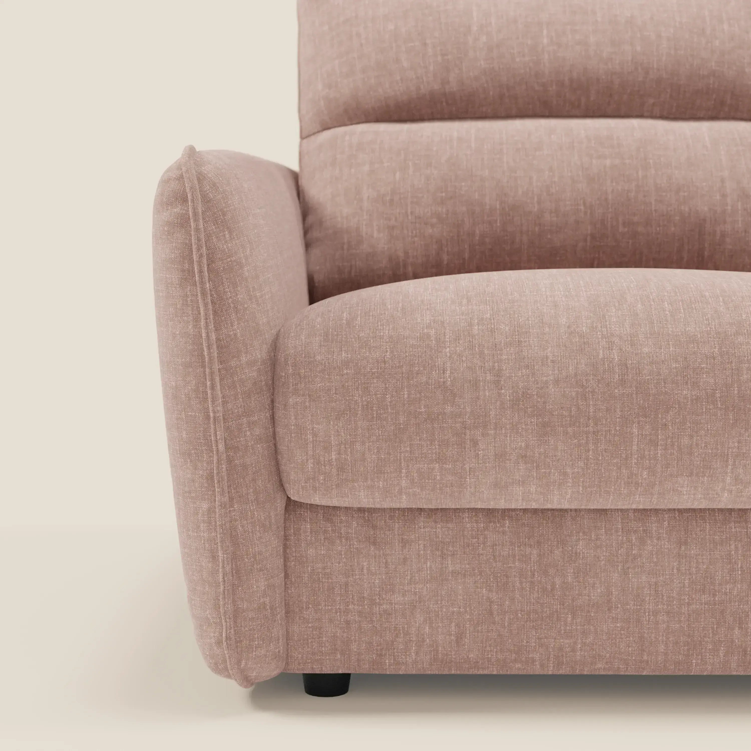 Primo piano del bracciolo sinistro e della seduta di Elios Divano letto con morbidi cuscini spalliera in tessuto smacchiabile T24 rosa cipria di Divani.Store, caratterizzato da un'imbottitura strutturata, curve morbide e gambe corte nere su sfondo crema.