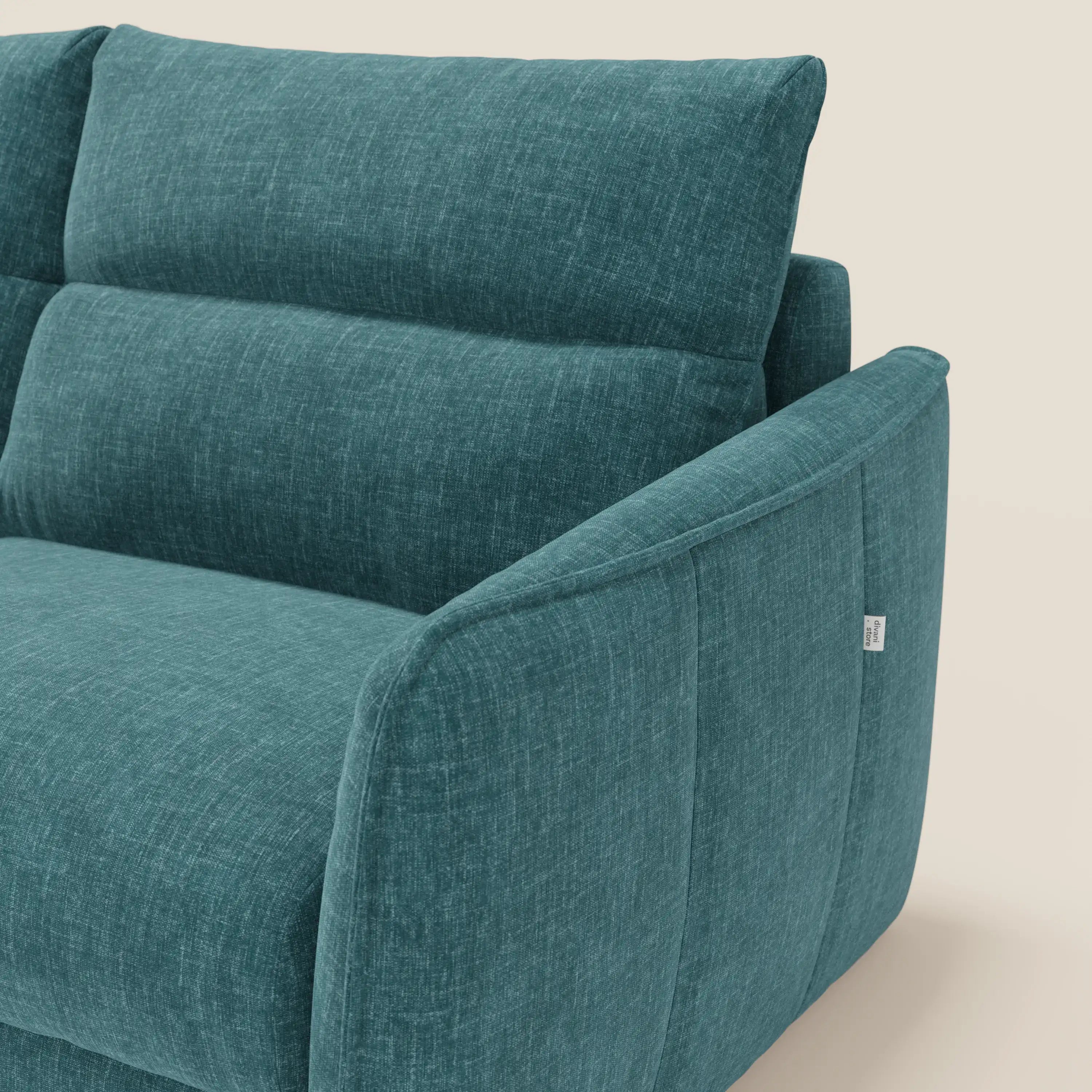 Primo piano del Divano letto Elios di Divani.Store, caratterizzato da cuscini di schienale in tessuto T24 petrolio smacchiabile, su uno sfondo chiaro con una piccola etichetta bianca sul bracciolo.