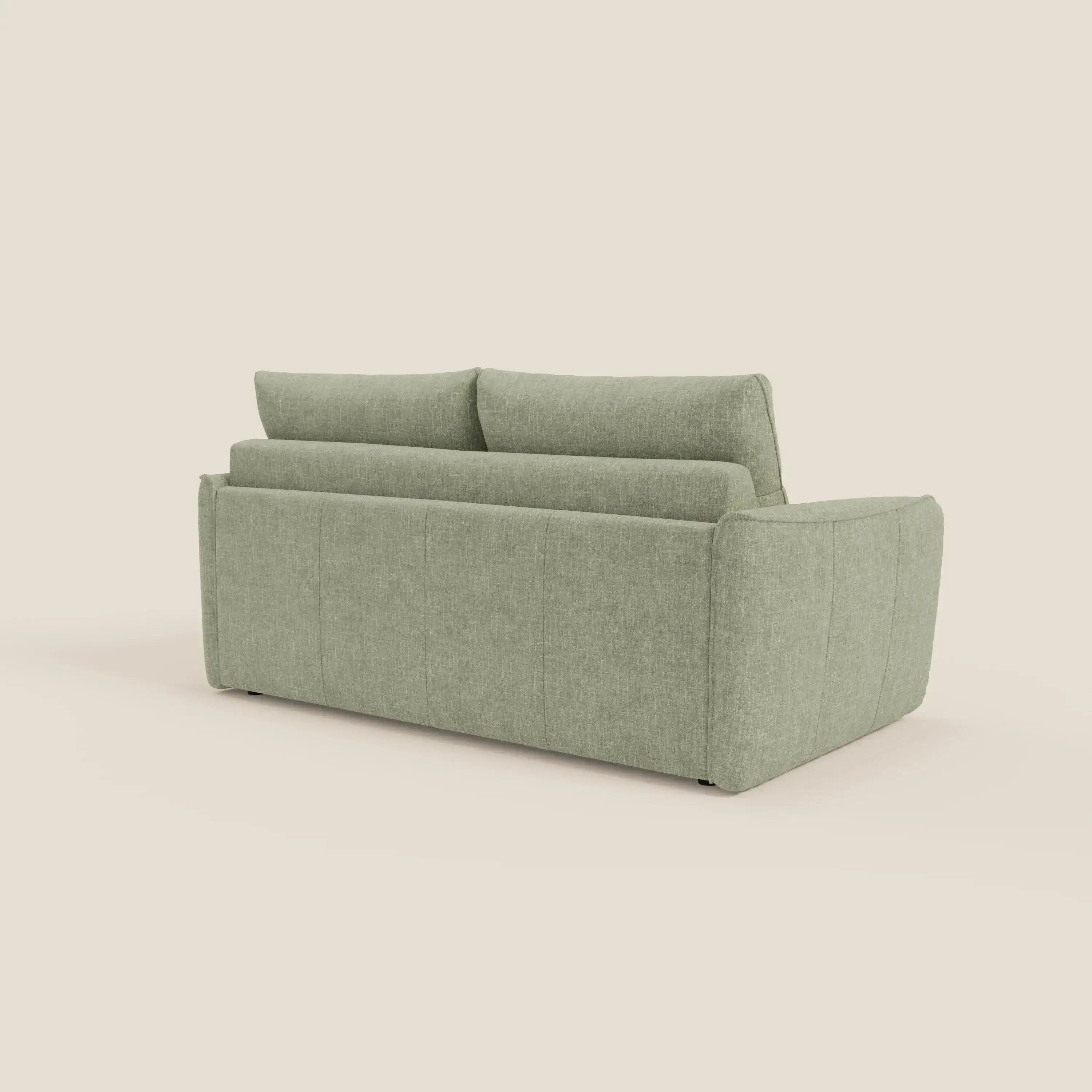 Elios Divano letto di Divani.Store è presentato dal retro, con morbidi cuscini dello schienale in tessuto T24 verde salvia antimacchia, linee pulite, braccioli arrotondati e cuciture a vista per un tocco moderno su uno sfondo bianco sporco.