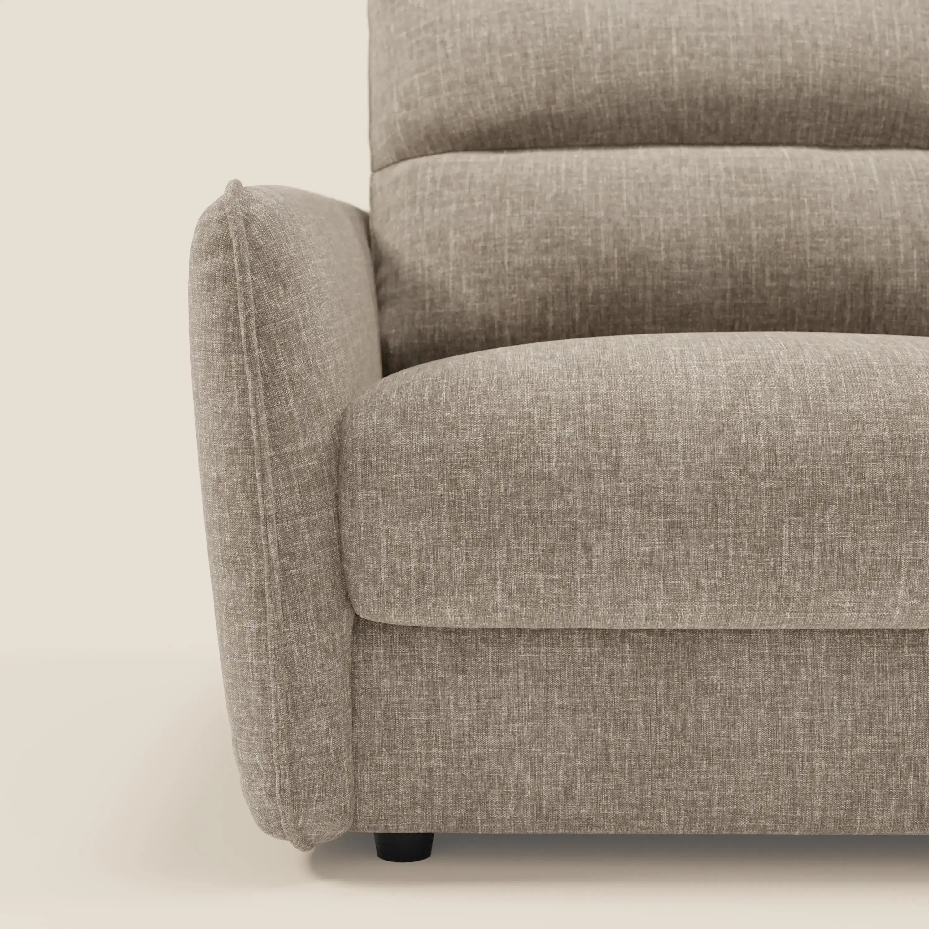 Primo piano del braccio sinistro e della seduta di Elios Divano letto con morbidi cuscini spalliera in tessuto smacchiabile T24 marrone tortora di Divani.Store, che mostra i cuscini in feltro e il tessuto antimacchia marrone chiaro su uno sfondo crema.