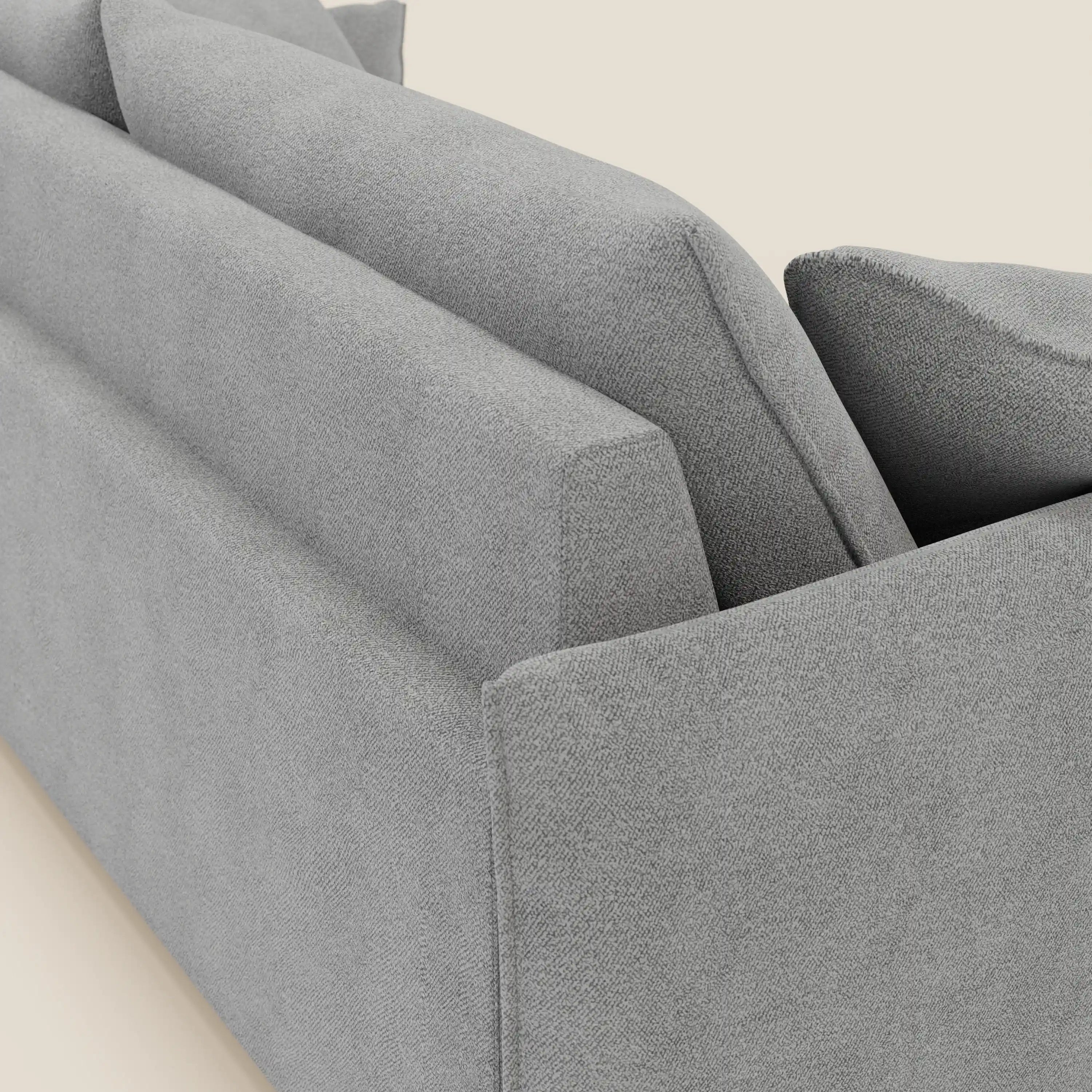 Un primo piano angolato del divano Flexar con sedute allungabili e schienale in piuma di Divani.Store, presentato in morbido bouclé impermeabile T07 grigio con due cuscini di schienale e braccioli angolari, su uno sfondo bianco sporco.