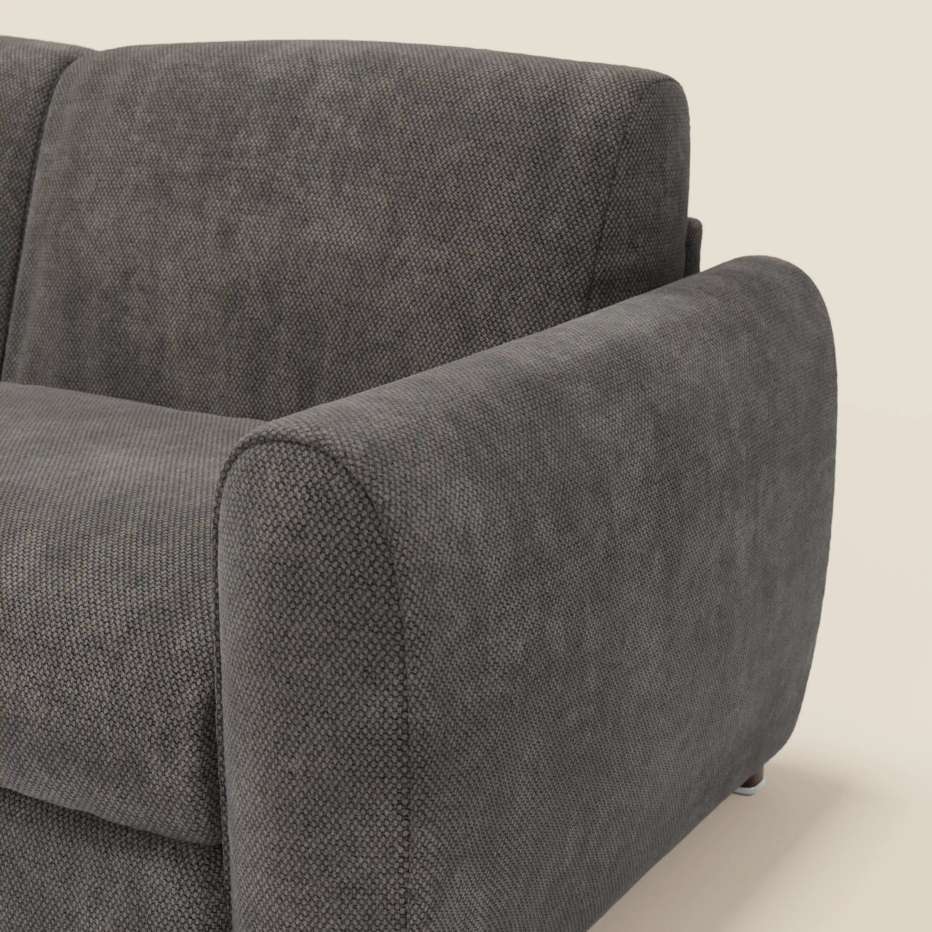 Primo piano del braccio destro e dello schienale del divano letto moderno Kaleo di Divani.Store, in raffinato tessuto impermeabile T26 antracite, che mette in evidenza l'imbottitura testurizzata e il bracciolo arrotondato in feltro su uno sfondo bianco sporco.