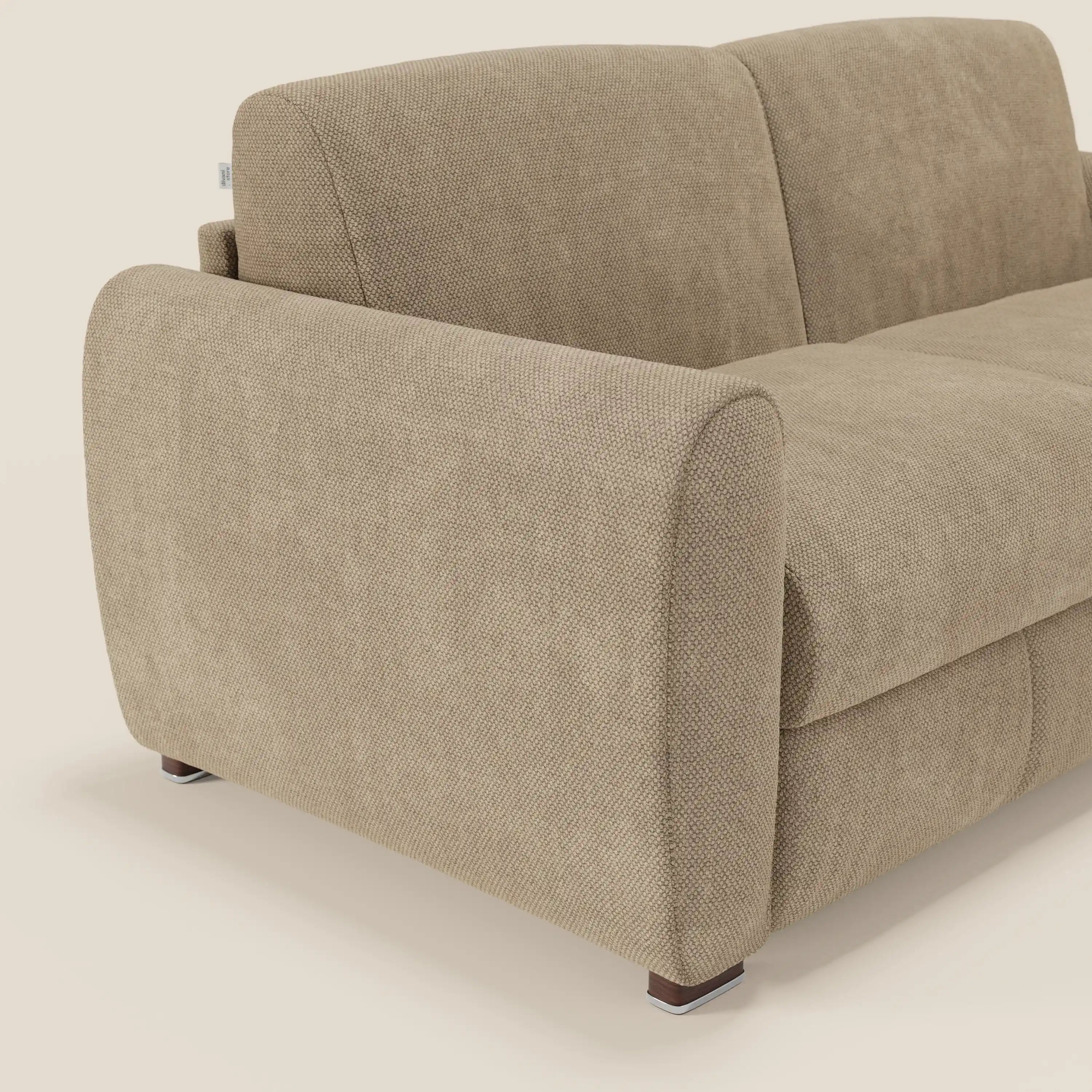 Primo piano del divano letto moderno Kaleo di Divani.Store, in tessuto impermeabile T26 beige, con imbottitura testurizzata, braccioli ampi e arrotondati, cuscini di schienale morbidi e gambe corte in legno scuro su uno sfondo beige chiaro.