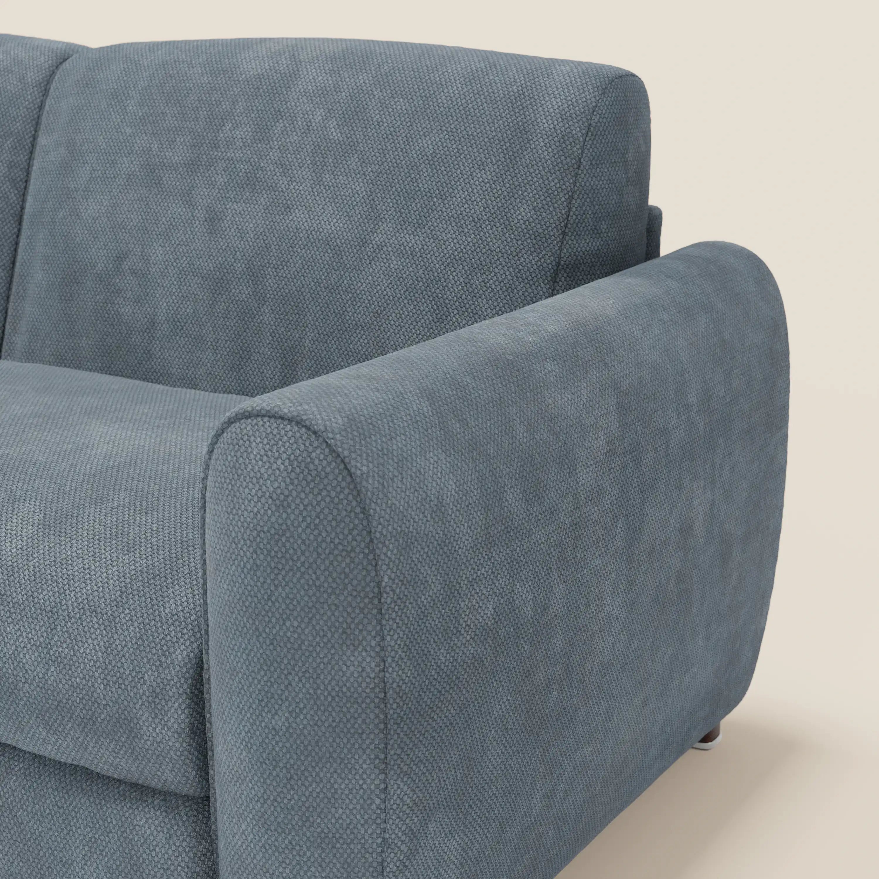 Primo piano del divano letto moderno Kaleo di Divani.Store in tessuto impermeabile T26 carta da zucchero, caratterizzato da bracciolo, schienale e cuscino di seduta spessi e dalla texture morbida con bordi arrotondati su uno sfondo beige chiaro.