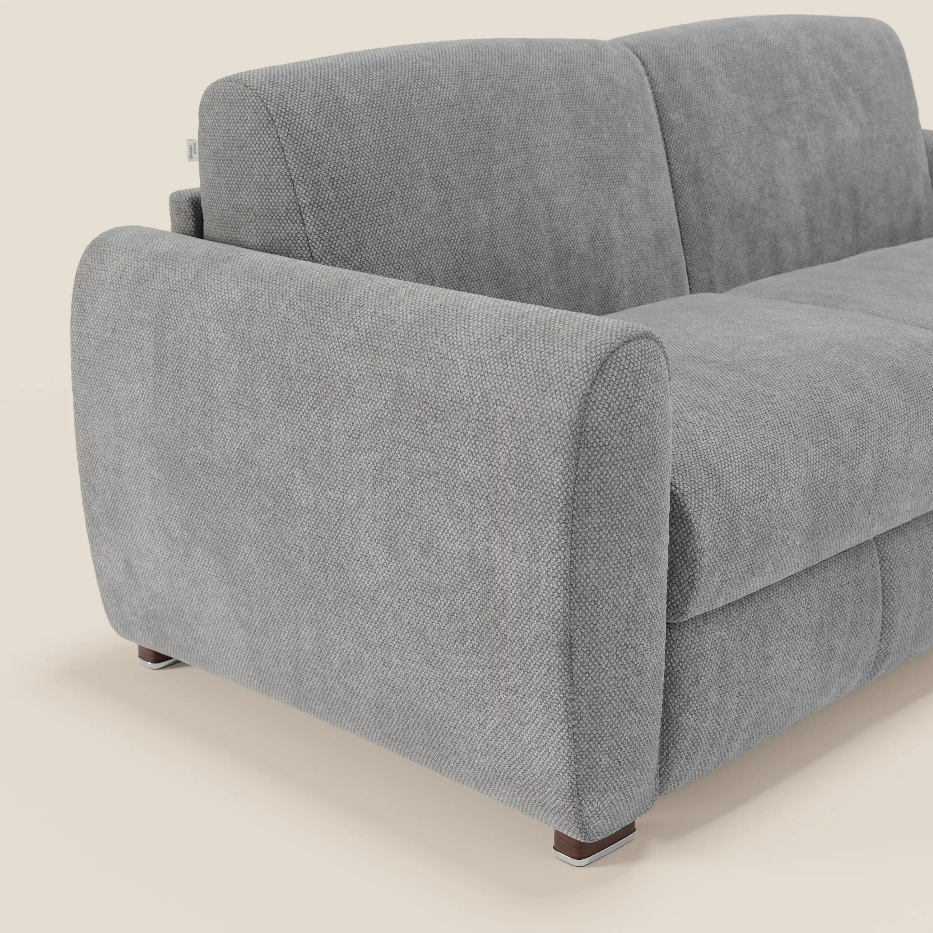 Primo piano del divano letto moderno Kaleo di Divani.Store, caratterizzato da tessuto impermeabile grigio T26, ampi braccioli arrotondati, schienali morbidi, gambe in legno scuro e design contemporaneo. Sullo sfondo beige è visibile solo una parte del divano a due posti.