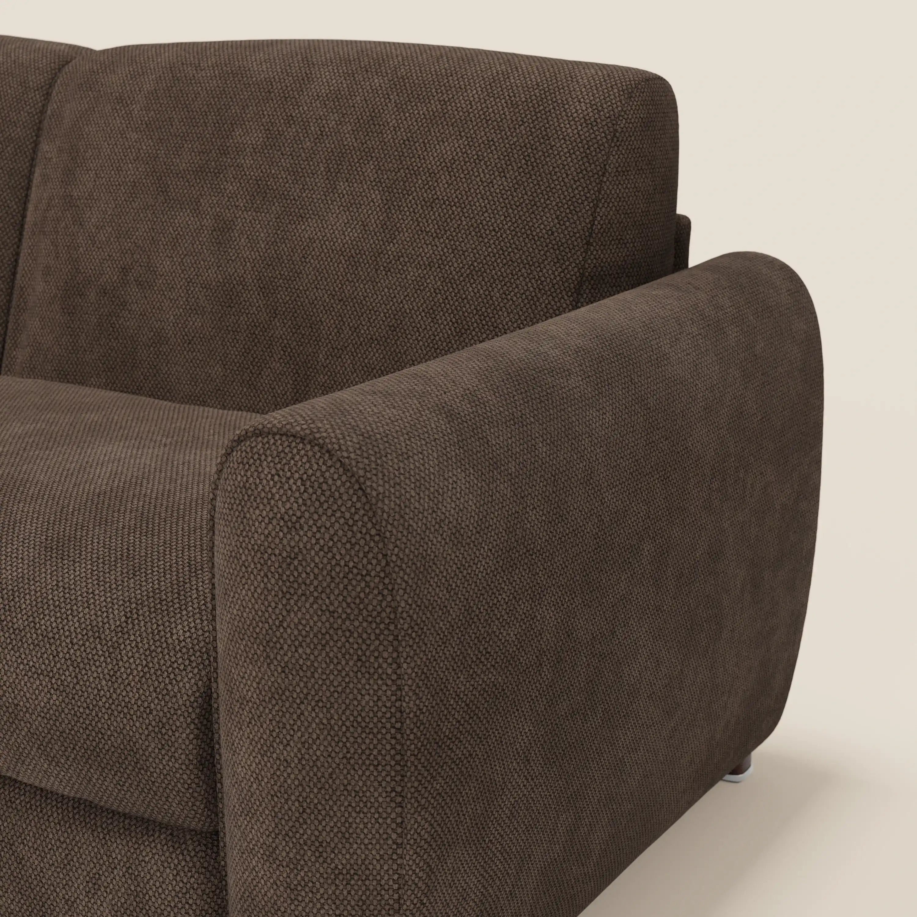 Primo piano del divano letto moderno Kaleo di Divani.Store, caratterizzato da un tessuto marrone T26 testurizzato e impermeabile e da bracciolo e schienale arrotondati. Il rivestimento scuro e contemporaneo contrasta con il fondo beige chiaro.