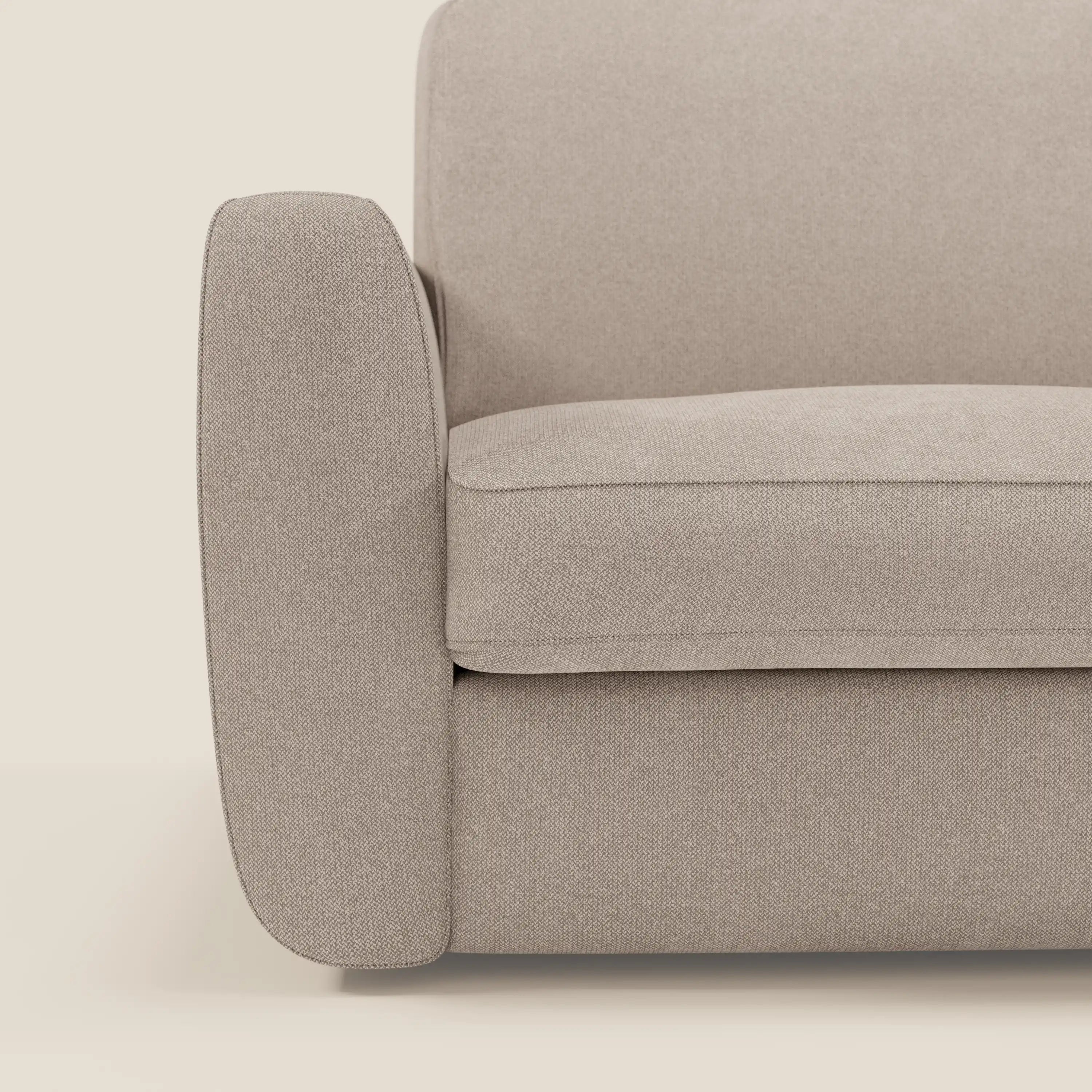 Primo piano del divano letto sfoderabile Leonida di Divani.Store in Smacchiabile T23 tortora, con bracciolo sinistro, cuscino di seduta e schienale. Le caratteristiche sono le linee pulite, il tessuto morbido e strutturato, il materasso H18 cm e il vano porta cuscini.