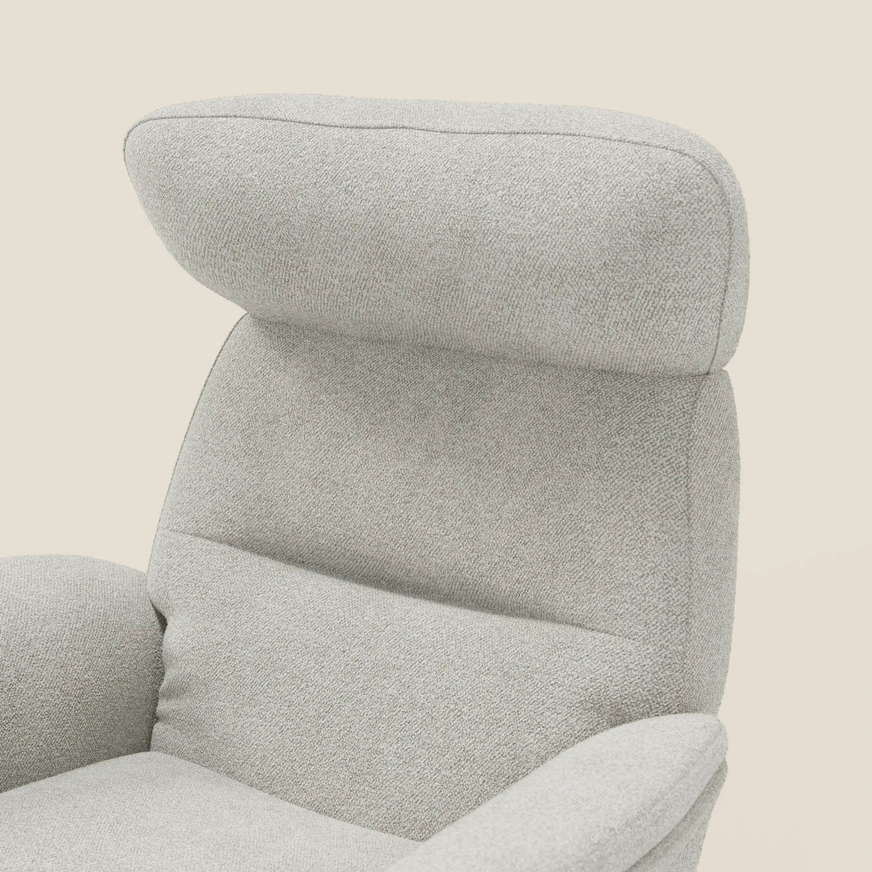 Primo piano della Poltrona relax reclinabile con pouf Lunor di Divani.Store, con schienale alto e poggiatesta imbottito, rivestita in bouclé impermeabile T07 bianco. Le sue linee moderne si stagliano su uno sfondo semplice di colore bianco sporco.