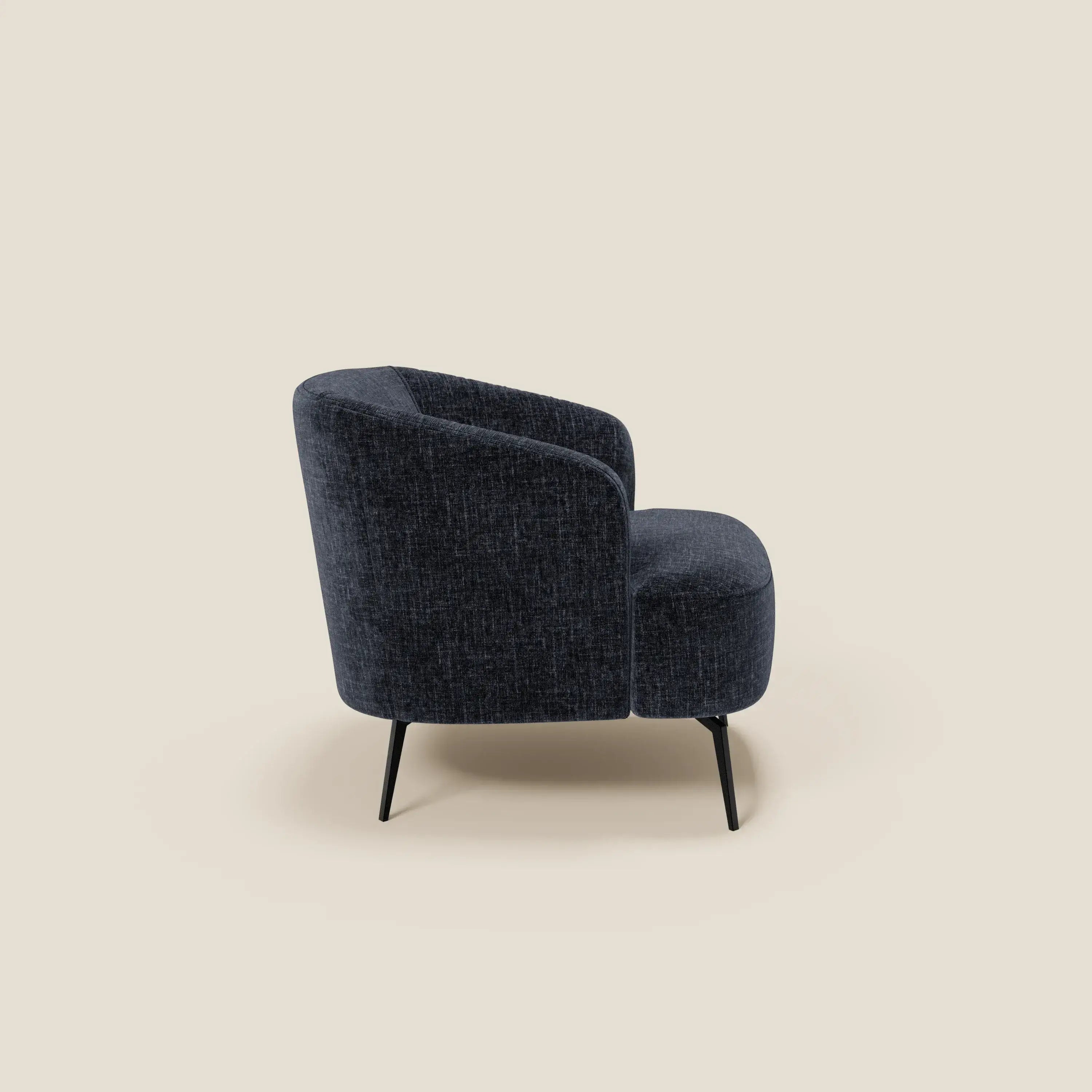 La poltroncina Renoa dall'eleganza moderna in tessuto smacchiabile T24 blu notte di Divani.Store è caratterizzata da schienale e seduta curvi, gambe sottili in metallo nero e viene presentata angolata a destra su uno sfondo beige chiaro.