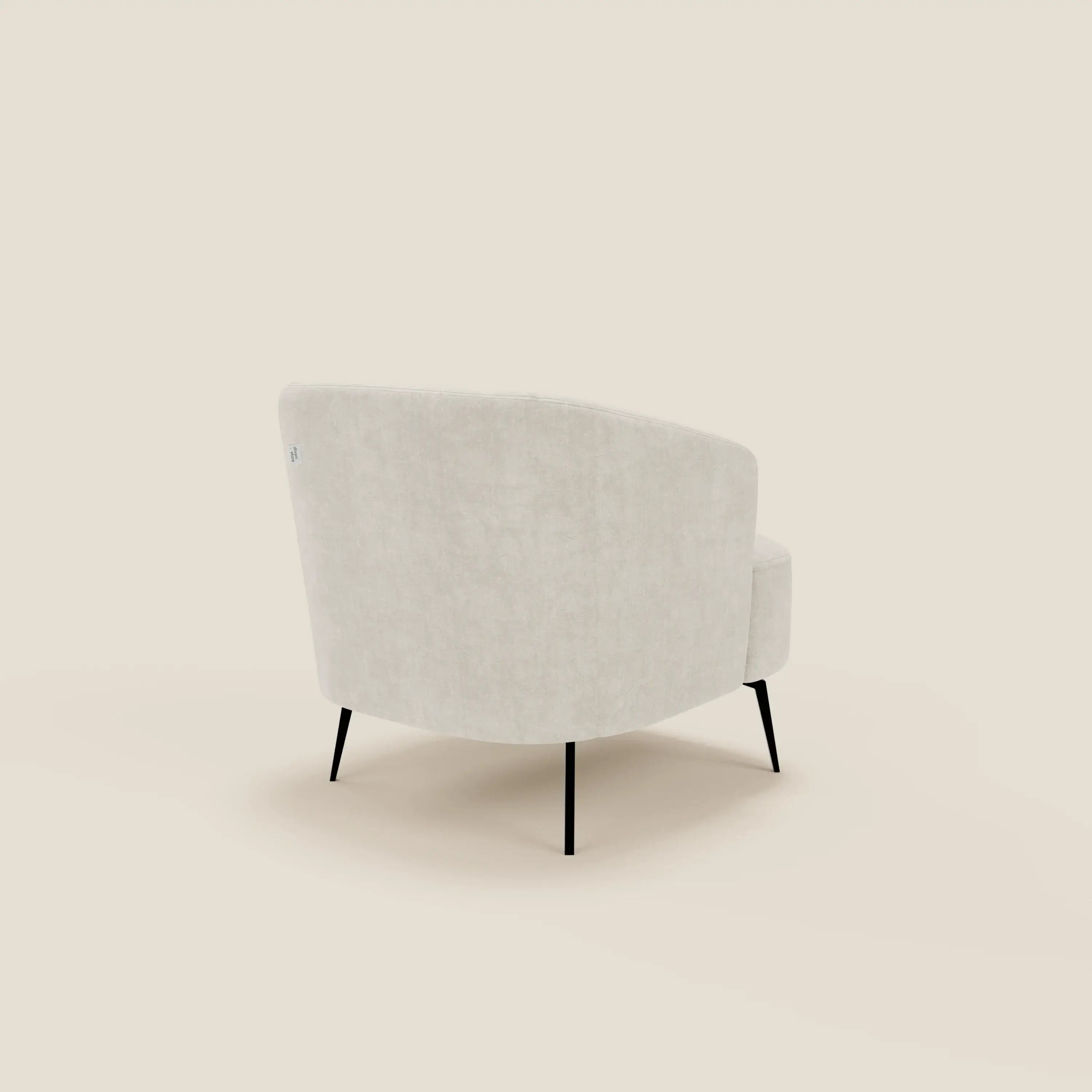La poltroncina Renoa dall'eleganza moderna in tessuto smacchiabile T24 bianco latte di Divani.Store viene mostrata angolata dal retro, con il suo design morbido e arrotondato e le sottili gambe nere su uno sfondo bianco sporco.