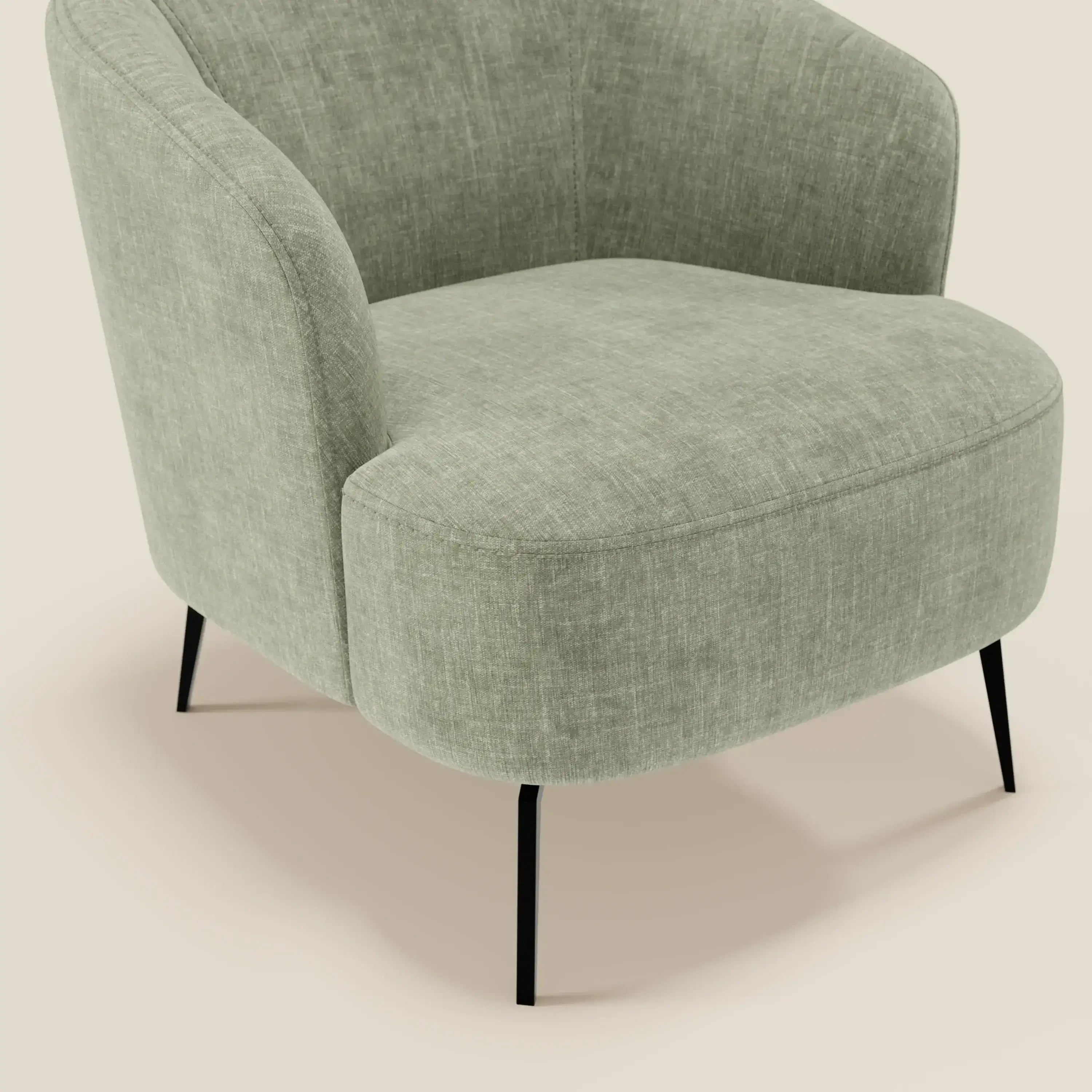 La poltroncina Renoa di Divani.Store è caratterizzata da un elegante tessuto smacchiabile T24 verde salvia, una silhouette moderna con schienale e braccioli arrotondati e quattro sottili gambe in metallo nero su sfondo beige chiaro.