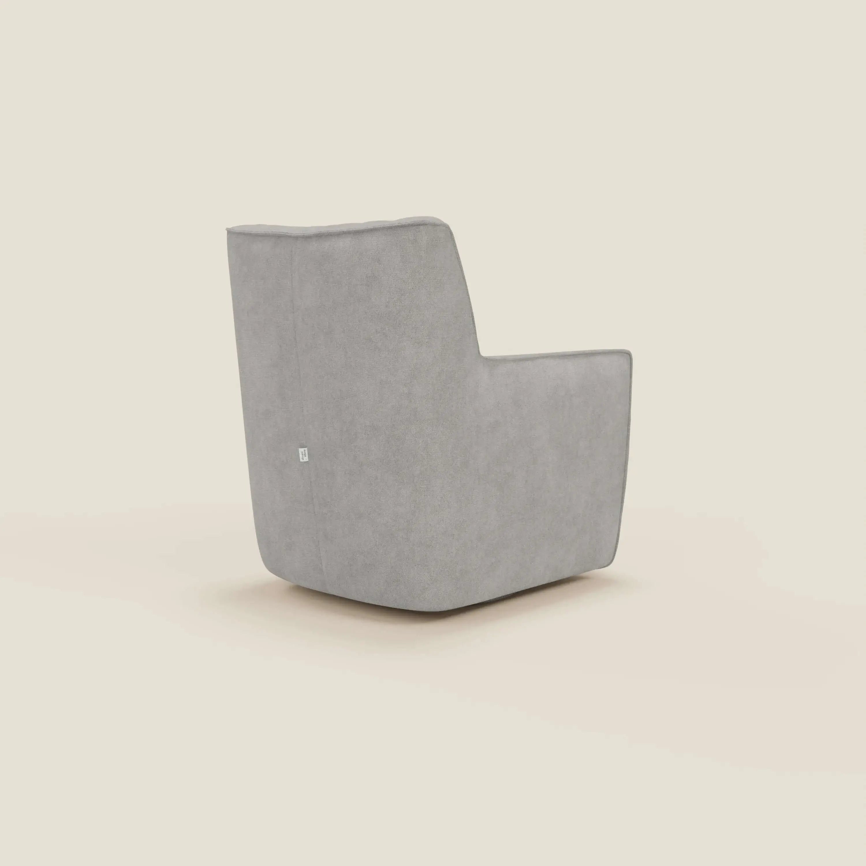 La poltrona girevole Tulla Poltrona girevole in tessuto impermeabile T02 grigio chiaro di Divani.Store è una poltrona girevole moderna e minimalista di colore grigio, con texture in tessuto morbido, silhouette squadrata, braccioli piatti e schienale leggermente reclinato su uno sfondo bianco sporco.