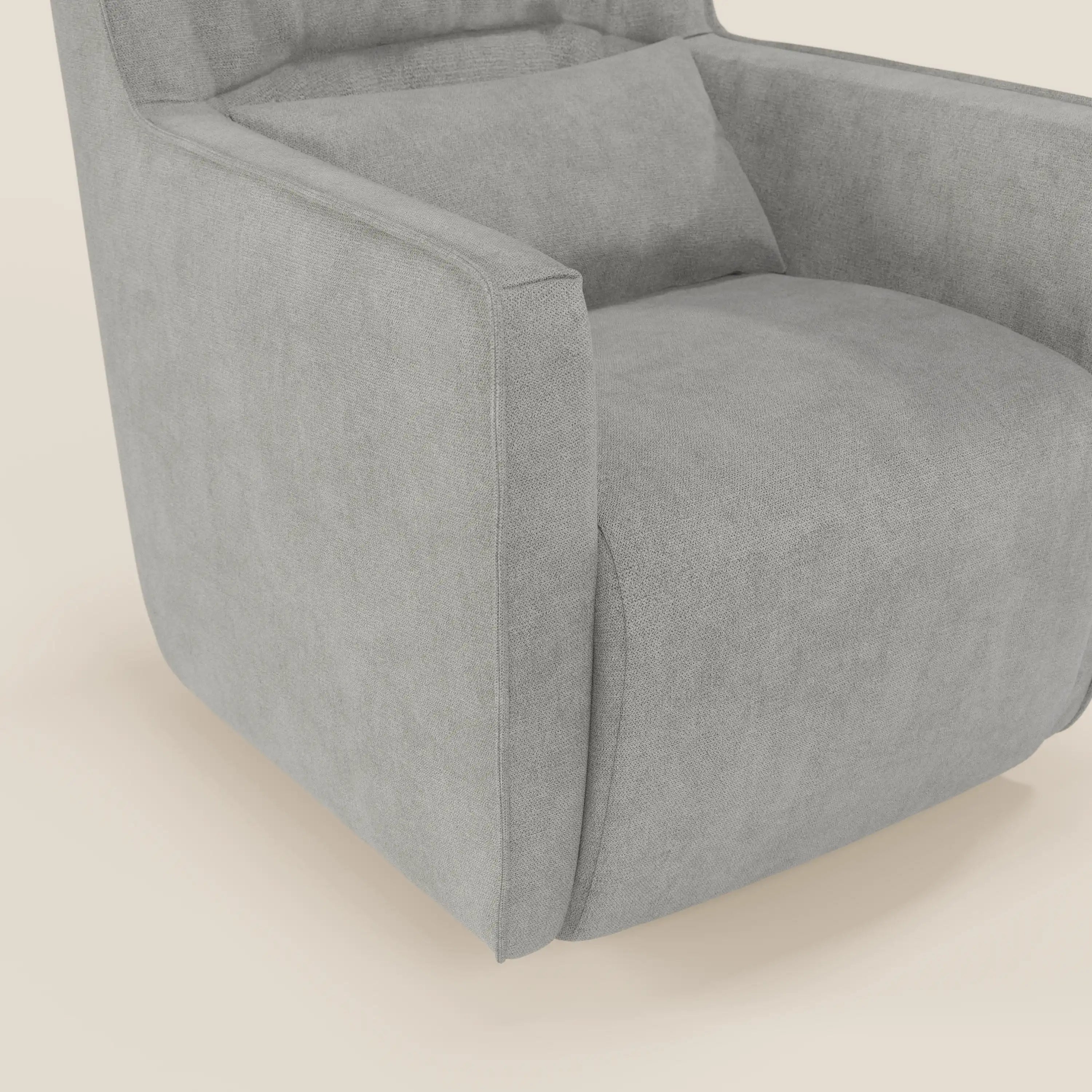 Un primo piano di Tulla Poltrona girevole in tessuto impermeabile T02 grigio chiaro di Divani.Store, che mostra la sua forma moderna e squadrata, le linee pulite, il cuscino coordinato e lo sfondo beige chiaro.