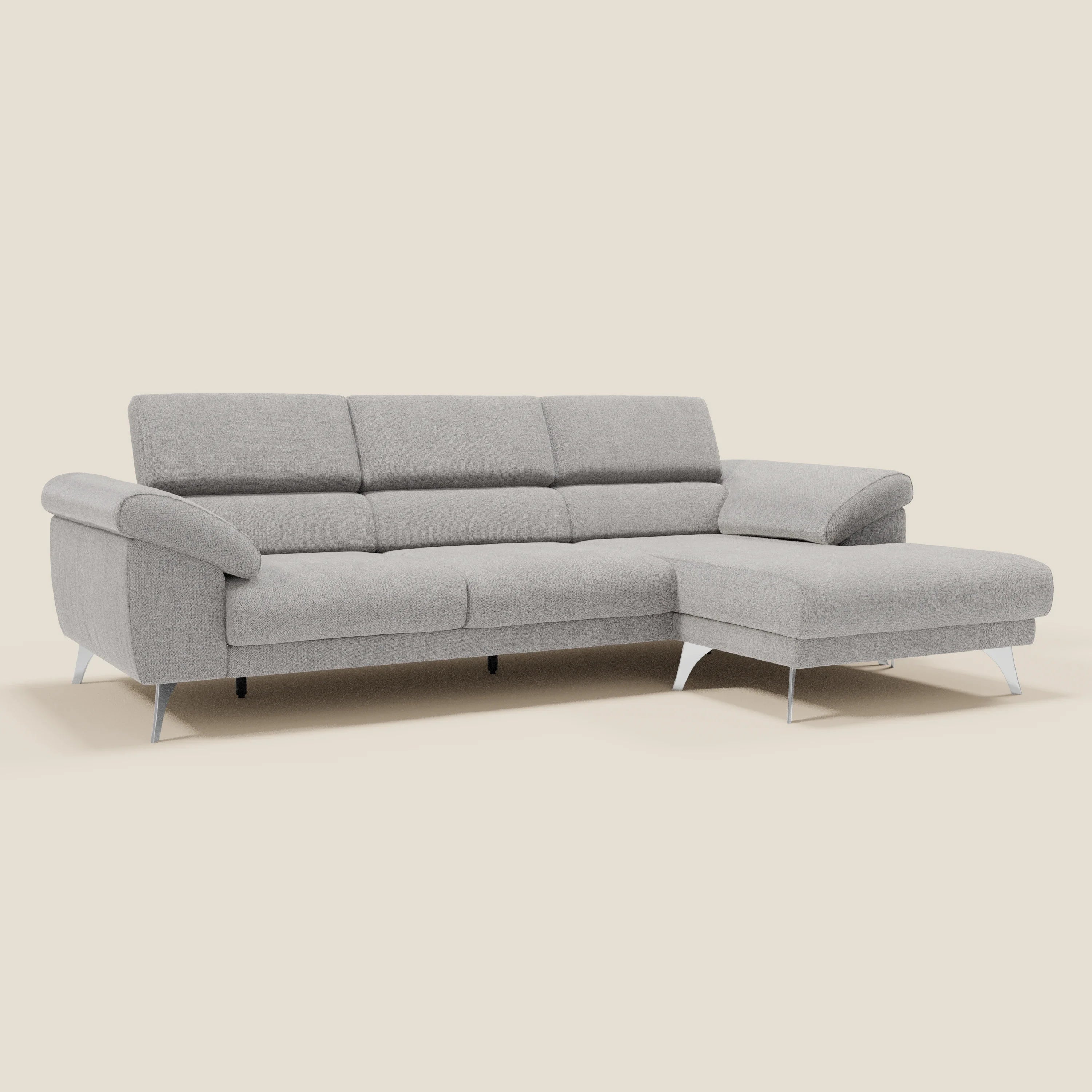 Il Divano angolare Donatello di Divani.Store, in morbido tessuto grigio T23 antimacchia, è caratterizzato da sedute scorrevoli, braccioli portaoggetti, poggiatesta e un design minimalista su uno sfondo beige neutro.