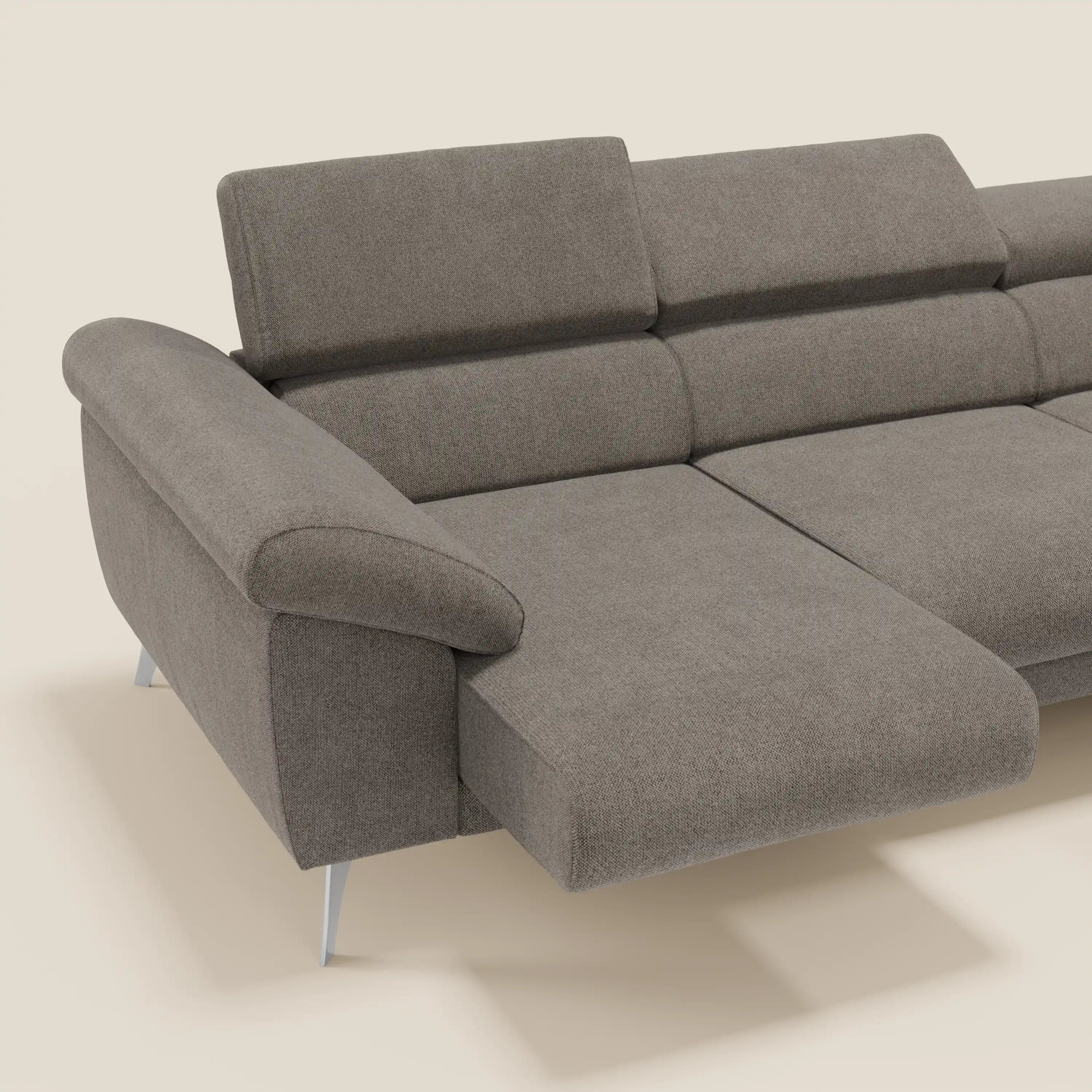 Il divano angolare Donatello di Divani.Store è caratterizzato da sedute scorrevoli, braccioli contenitore e poggiatesta in morbido tessuto talpa T23 antimacchia. Su uno sfondo in tinta unita beige chiaro.