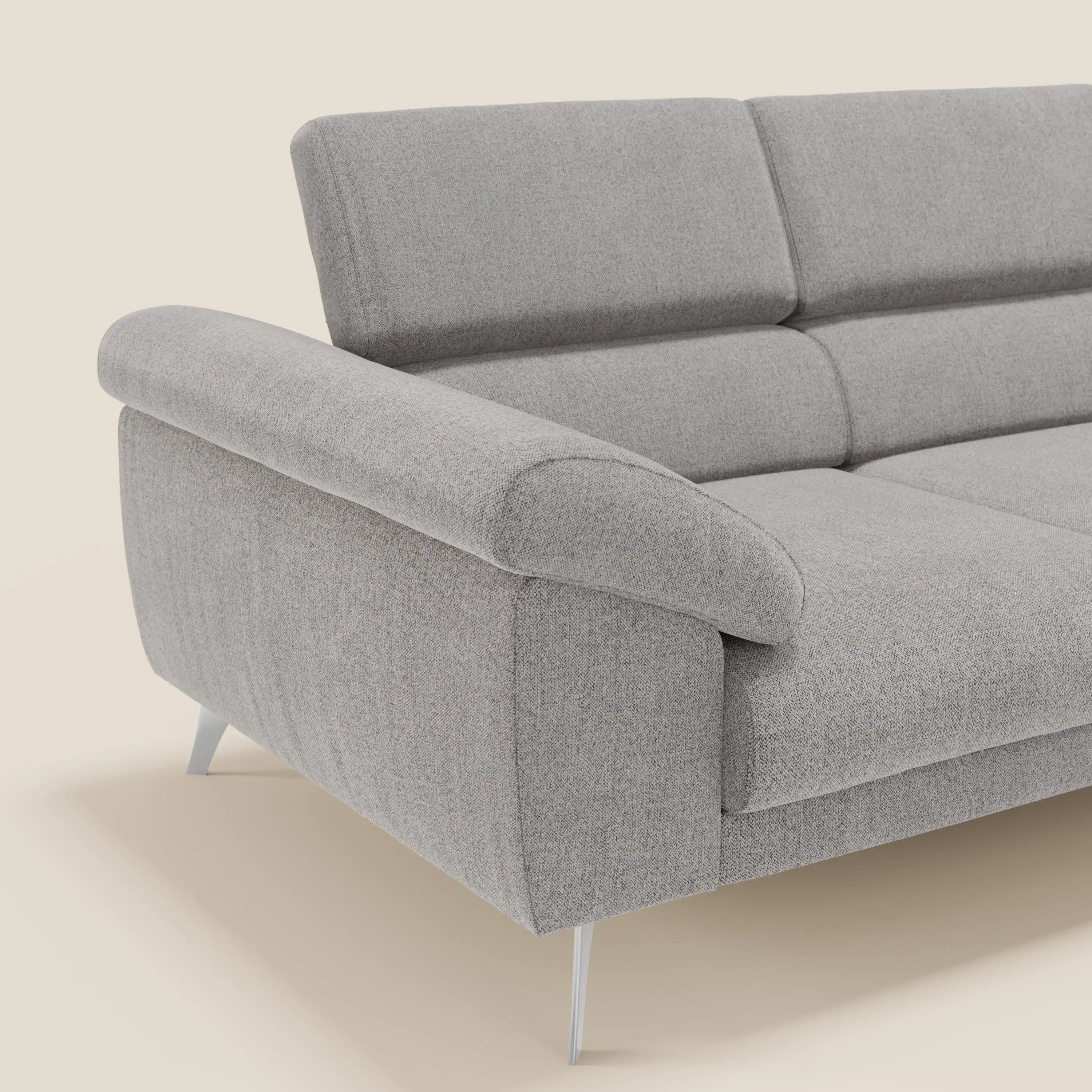 Il divano Donatello con 3 sedute allungabili di Divani.Store è caratterizzato da tessuto T23 grigio antimacchia, ampi braccioli imbottiti con portaoggetti, poggiatesta reclinabili, imbottitura soffice e gambe angolate in metallo. Le linee eleganti si adattano agli interni moderni. Solo un'estremità è mostrata su uno sfondo bianco sporco.