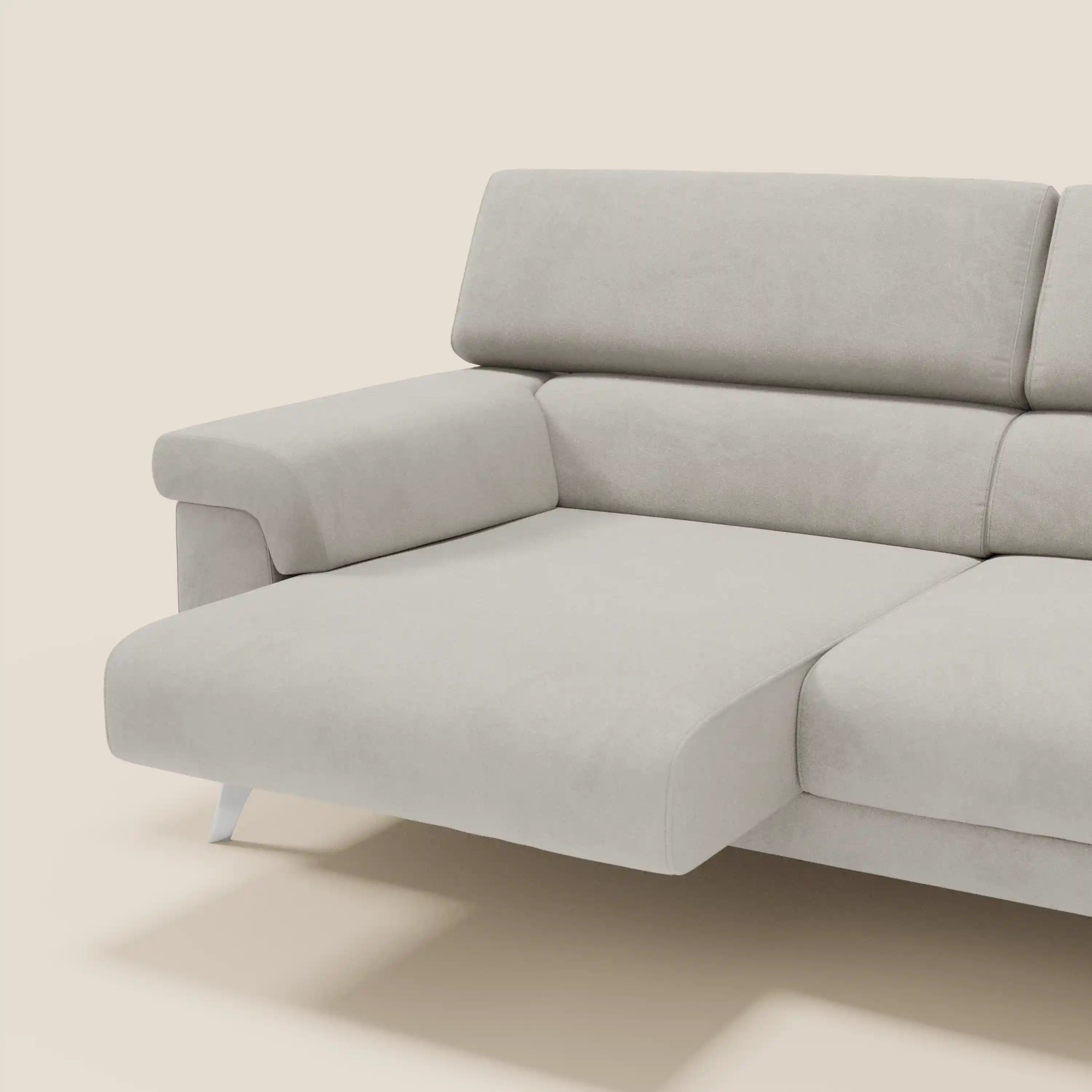 Il divano componibile Raffaello di Divani.Store è caratterizzato da sedute allungabili e poggiatesta regolabili in microfibra panna T11 antimacchia, con linee eleganti e gambe basse in metallo, su uno sfondo beige chiaro per un tocco moderno.