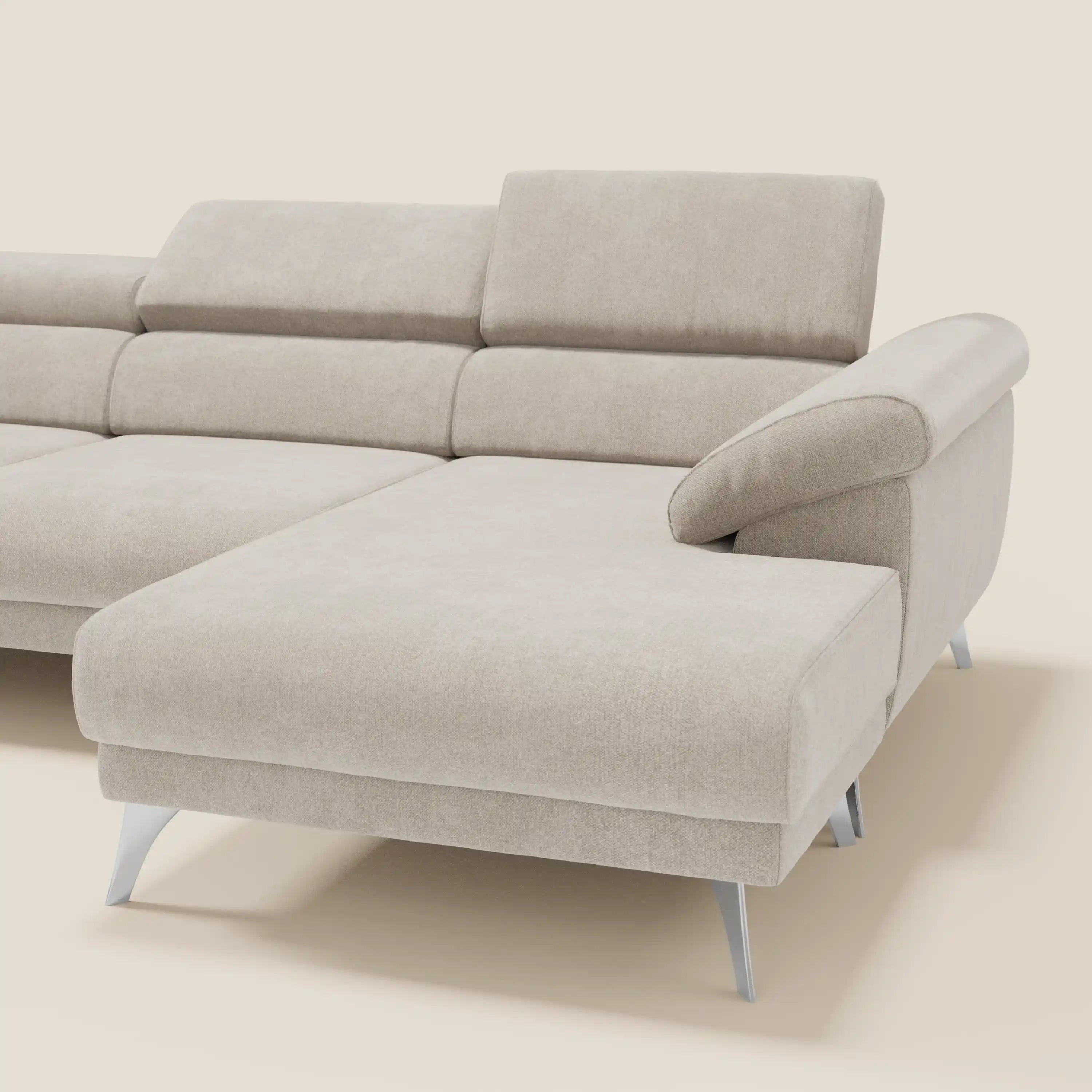 Il divano angolare Donatello di Divani.Store in tessuto smacchiabile panna presenta sedute scorrevoli, braccioli contenitore, poggiatesta regolabili e un design moderno su gambe in metallo, presentato su sfondo crema.