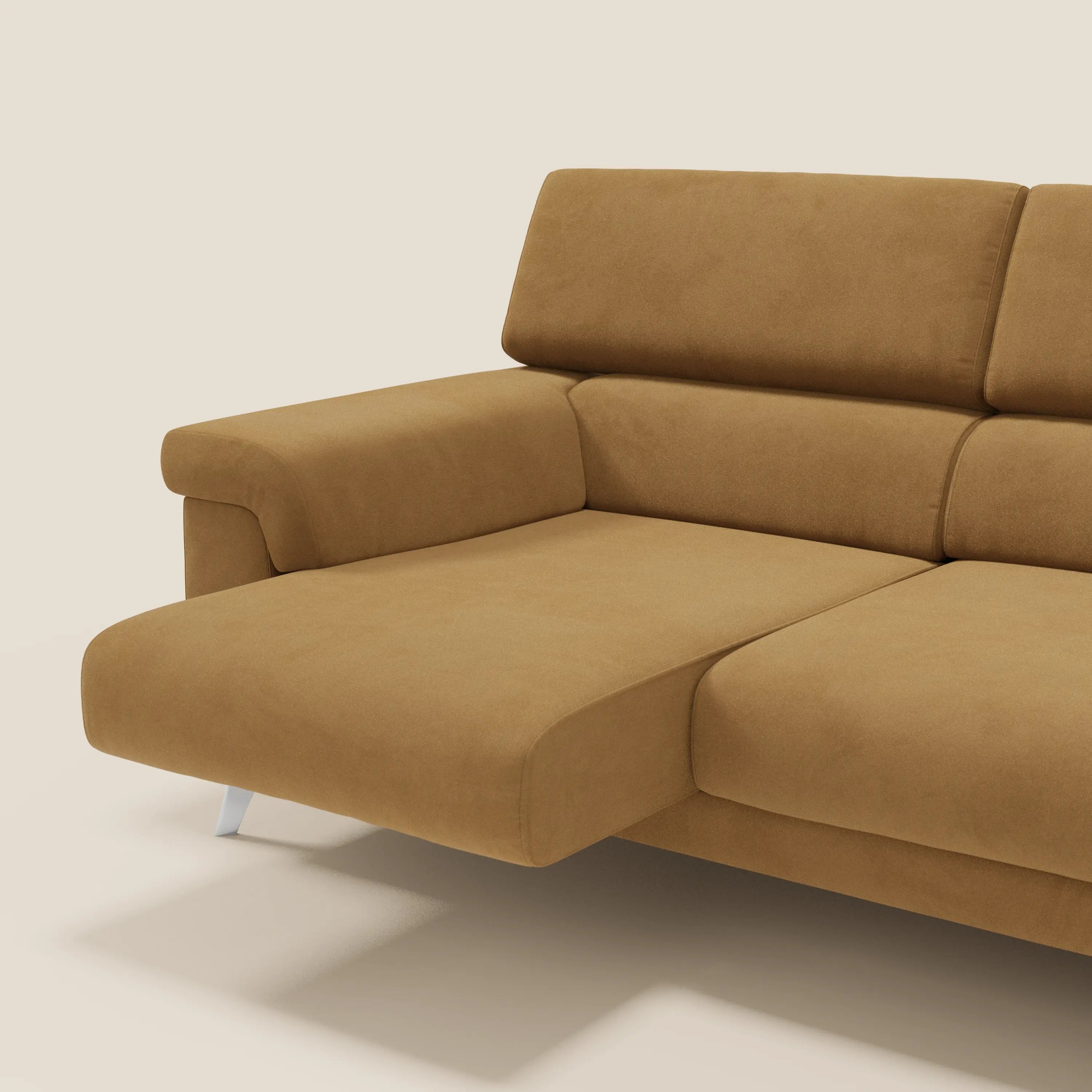 Un primo piano del divano angolare Raffaello di Divani.Store in T11 cuoio microfibra smacchiabile, caratterizzato da sedute scorrevoli, poggiatesta regolabili, cuscini in peluche ed eleganti gambe argentate su uno sfondo beige chiaro.