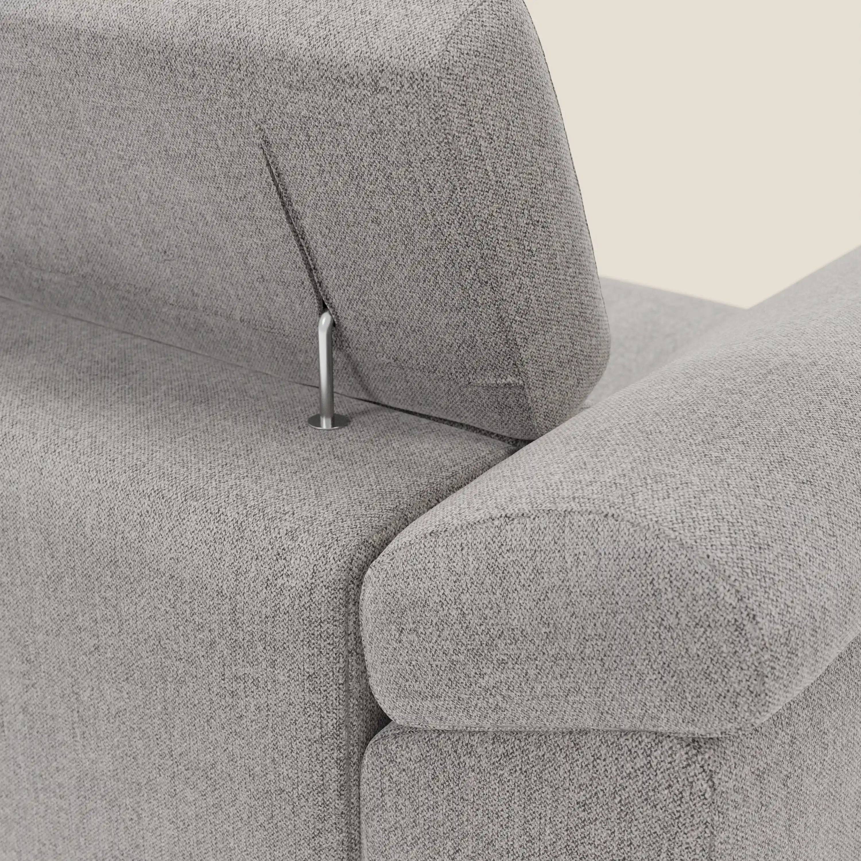 Un primo piano del divano angolare Donatello di Divani.Store in tessuto smacchiabile grigio T23 mostra la poggiatesta regolabile con asta metallica a vista, l'imbottitura intrecciata e i braccioli con contenitore.