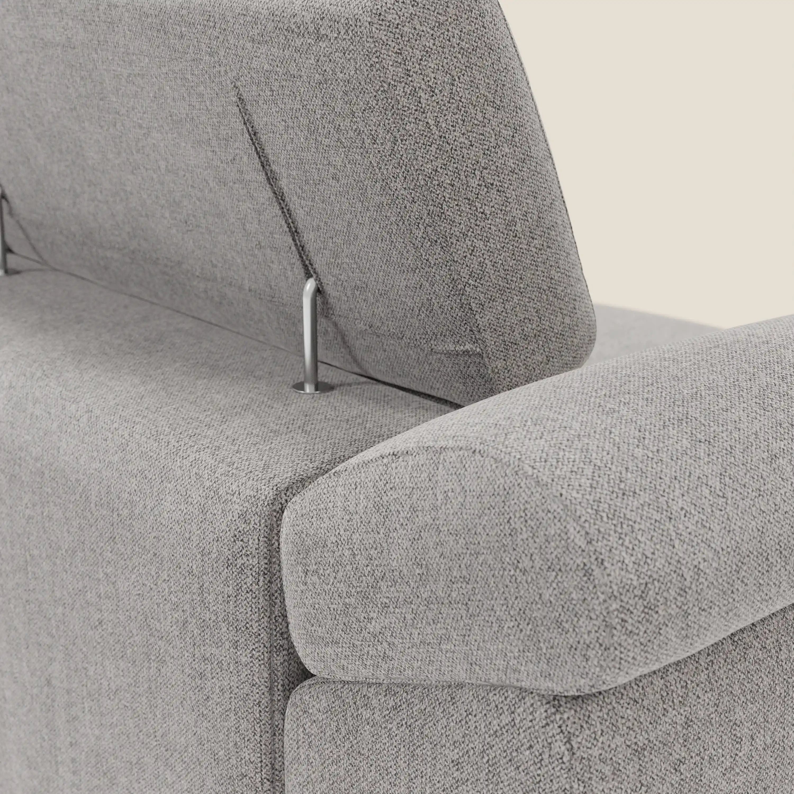 Primo piano del divano Donatello con 3 sedute allungabili di Divani.Store in tessuto smacchiabile T23 grigio, caratterizzato da una finitura strutturata e da un poggiatesta regolabile con supporto in metallo per il posizionamento in piedi o in piano.
