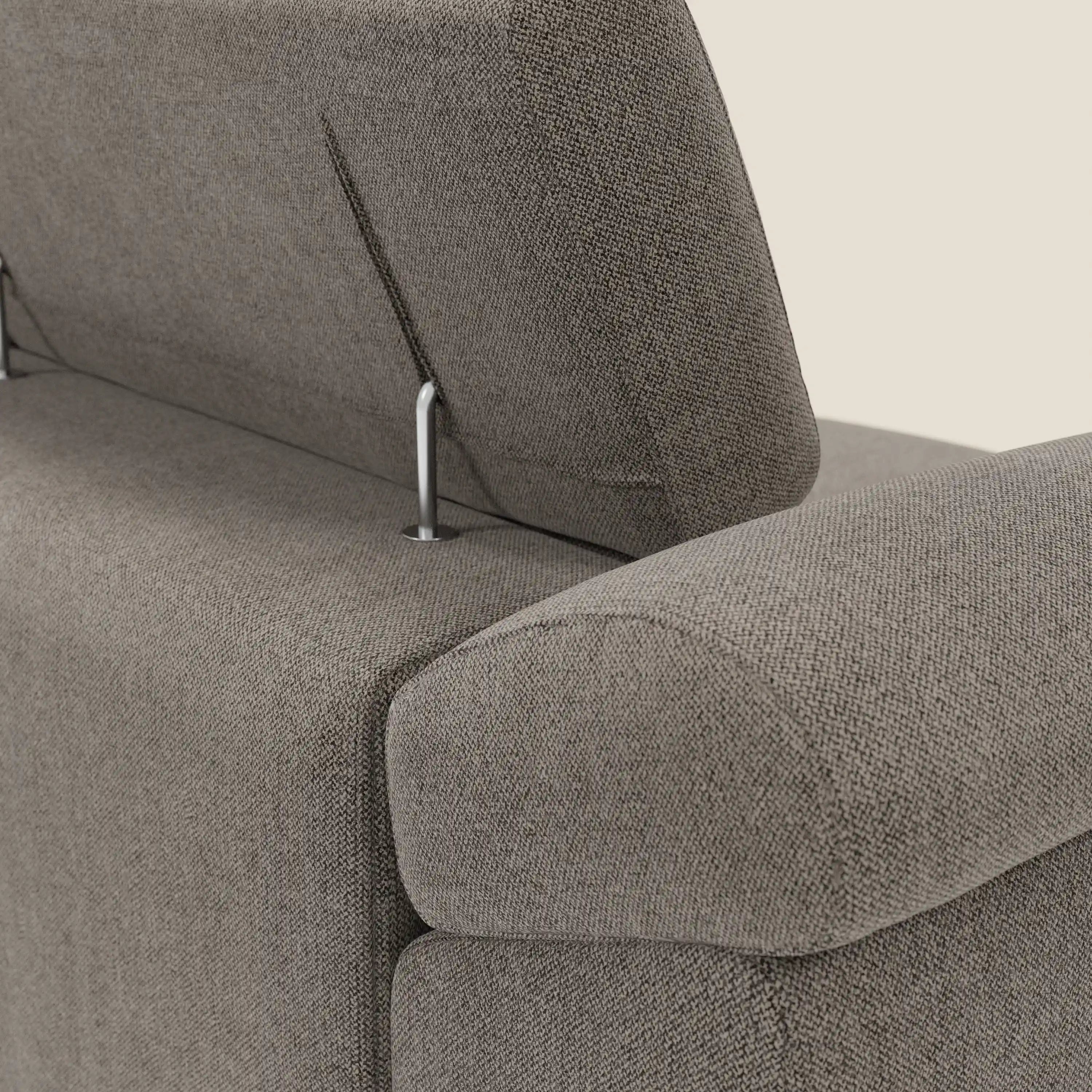 Primo piano del divano Donatello di Divani.Store in tessuto smacchiabile T23 talpa, con 3 sedute allungabili, braccioli contenitori e poggiatesta regolabili su aste cromate, perfetto per gli amanti del comfort moderno. Trama strutturata su sfondo beige tinta unita.
