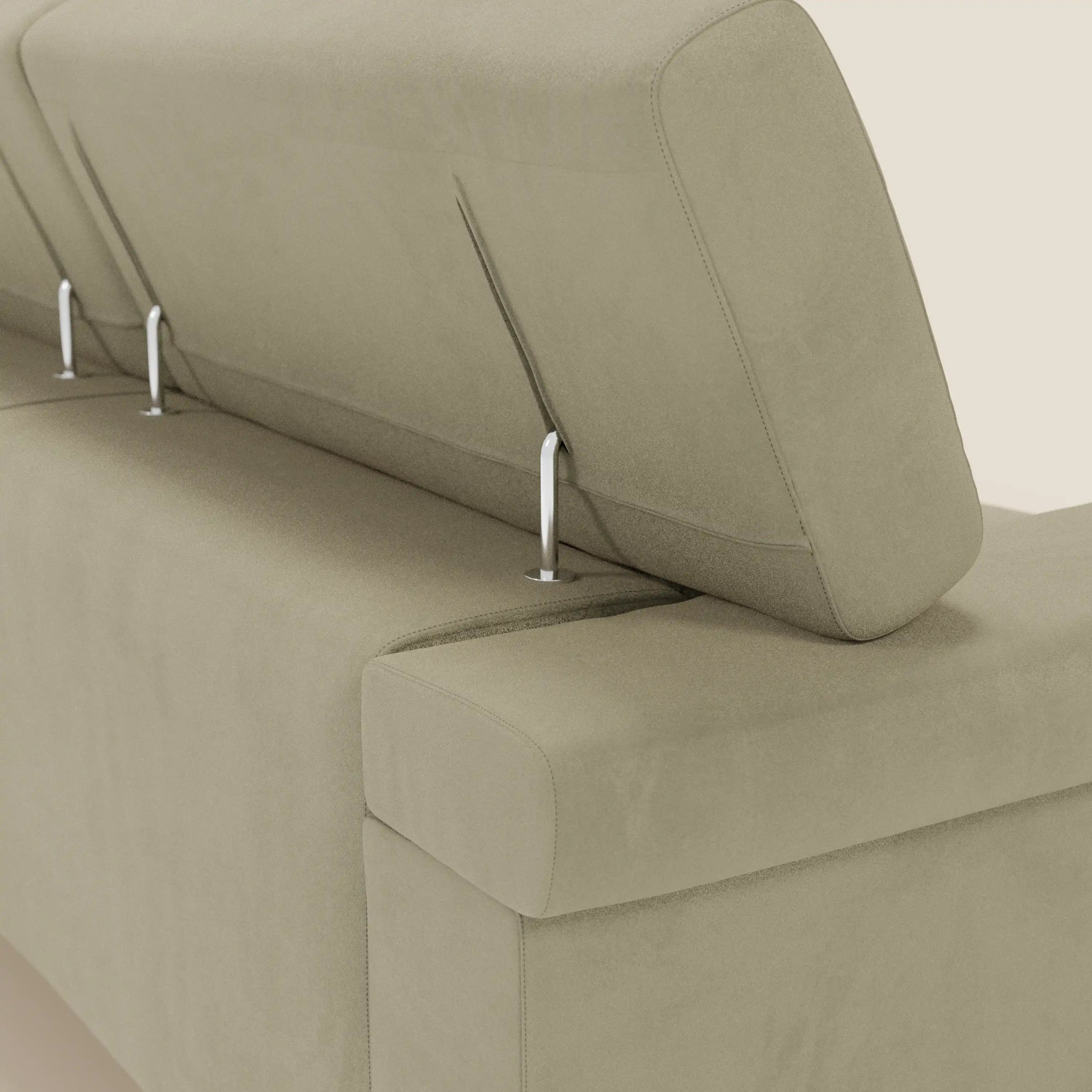 Un primo piano del Raffaello Divano angolare di Divani.Store ne mostra il rivestimento in microfibra beige antimacchia e le linee moderne. Un poggiatesta regolabile è sollevato su aste metalliche e rivela il meccanismo di inclinazione su uno sfondo neutro.