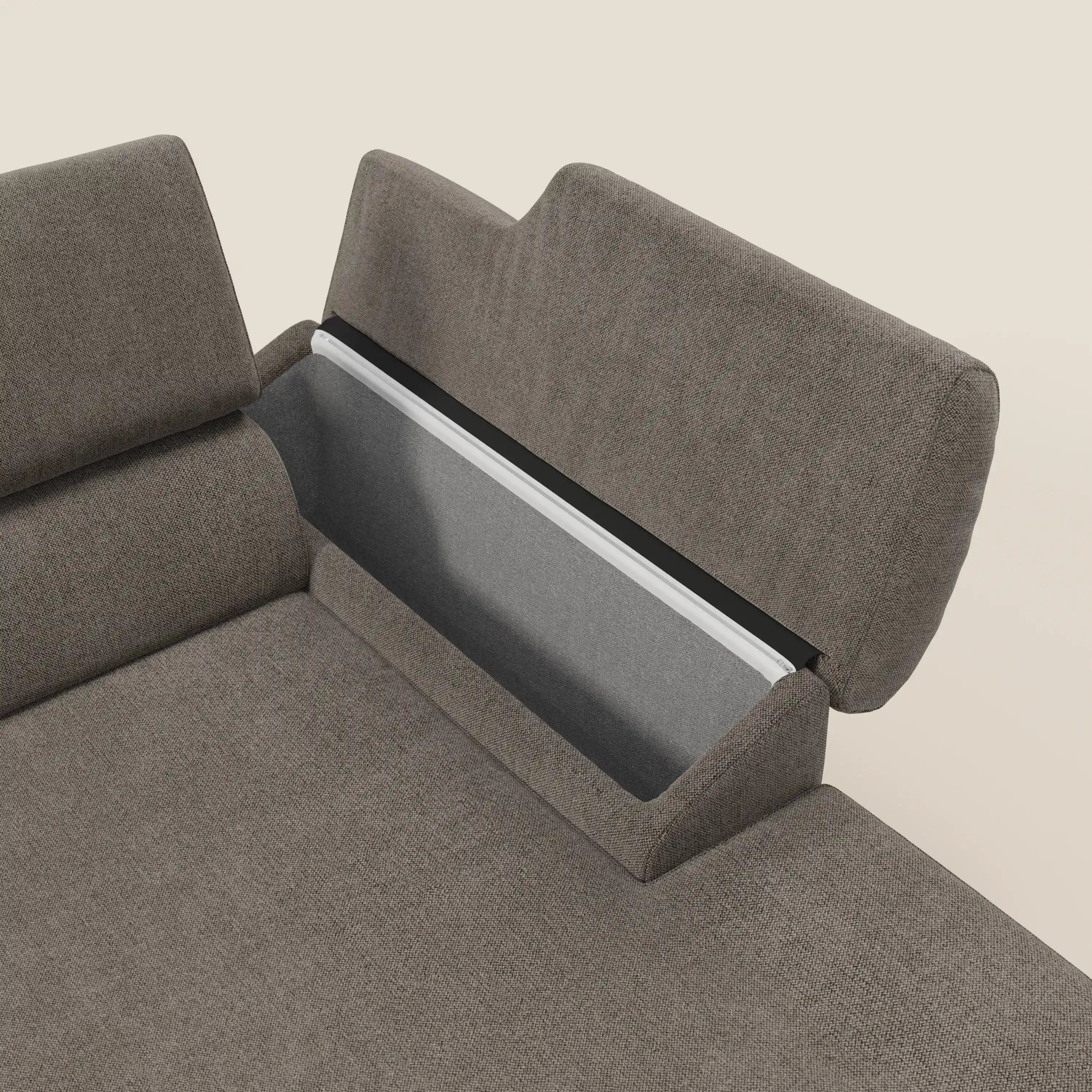 Un primo piano del Divano angolare Donatello di Divani.Store in talpa T23 mostra le sedute scorrevoli, i braccioli portaoggetti e il poggiatesta con vano portaoggetti grigio incernierato: un connubio di comfort evoluto e design intelligente su uno sfondo semplice.