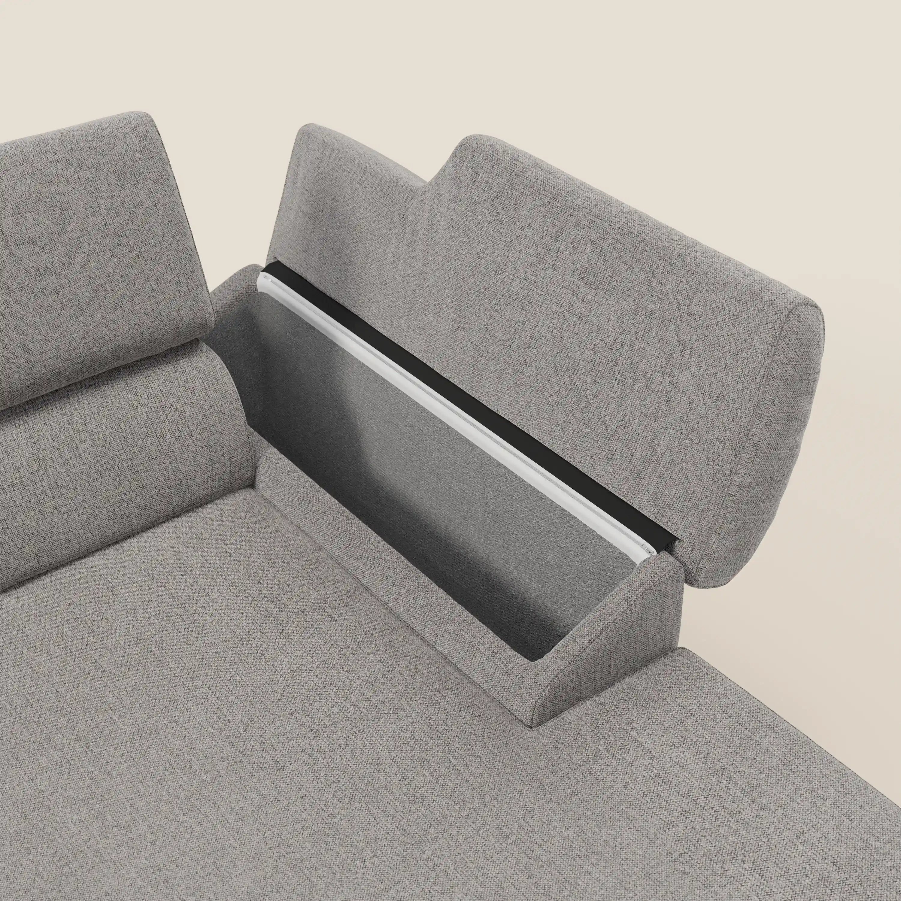 Primo piano del Divano angolare Donatello di Divani.Store in tessuto antimacchia grigio T23, caratterizzato da sedute e braccioli scorrevoli con vani portaoggetti. Lo schienale è aperto per offrire spazio agli oggetti, su un semplice sfondo bianco sporco.