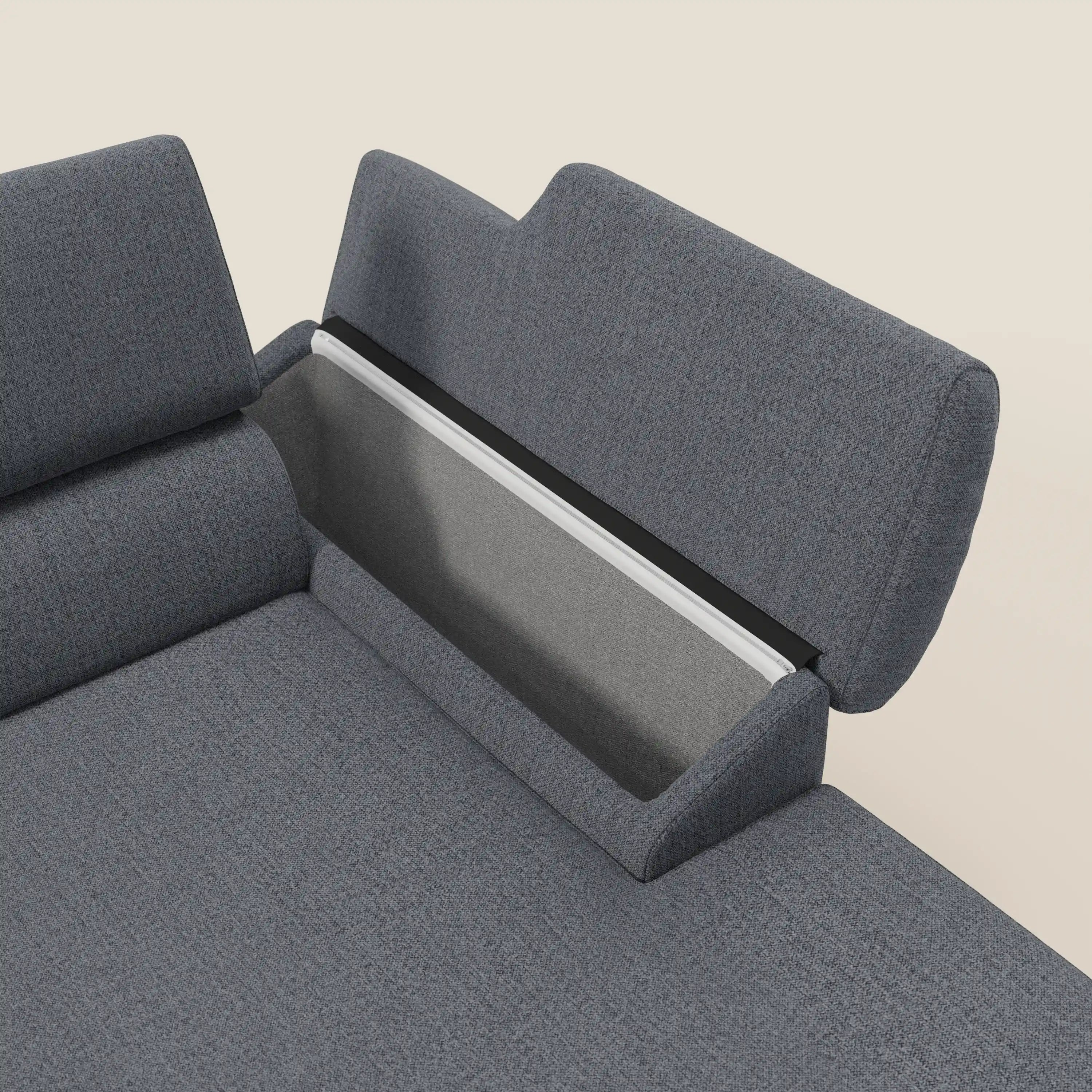 Un primo piano del Donatello Divano angolare di Divani.Store in grafite T23 blu mostra i sedili scorrevoli, il vano portaoggetti nel bracciolo e il vano foderato dietro lo schienale con un accento bianco, su uno sfondo beige chiaro.