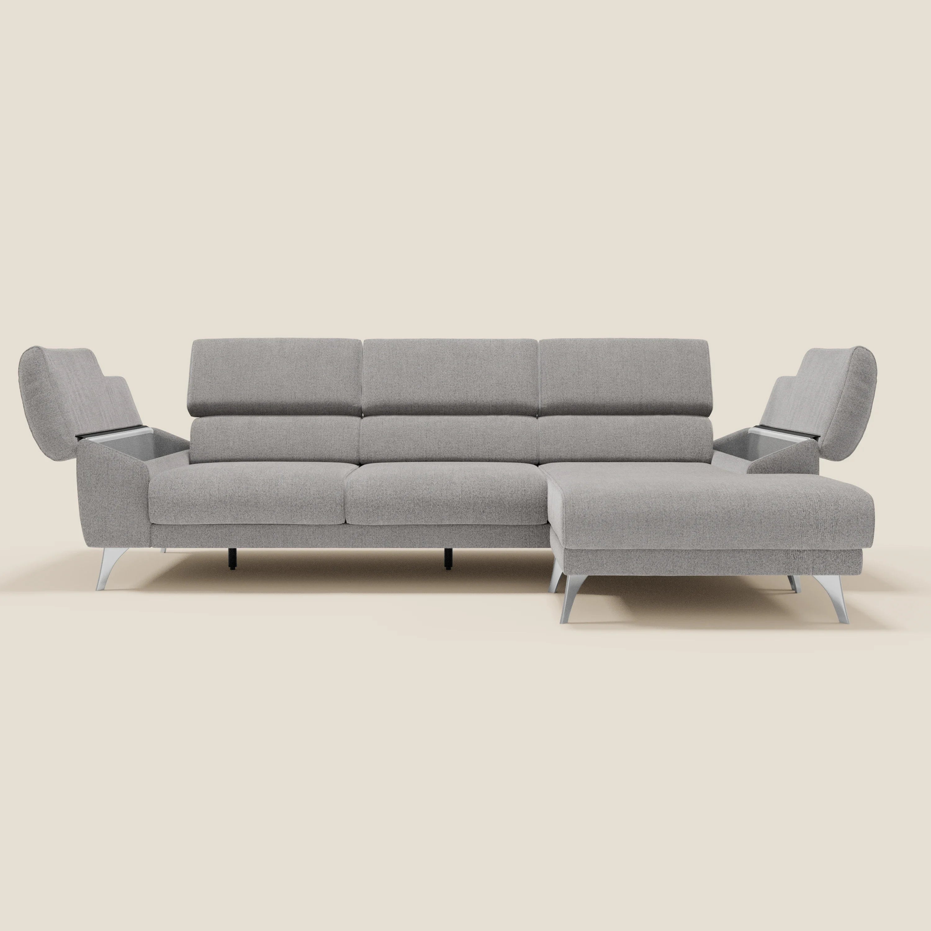 Il Divano angolare Donatello di Divani.Store, in morbido tessuto antimacchia grigio T23, è caratterizzato da sedute scorrevoli, braccioli portaoggetti e poggiatesta regolabili. La sua forma a L a 5 posti offre un'estensione della chaise lounge su uno sfondo beige chiaro.